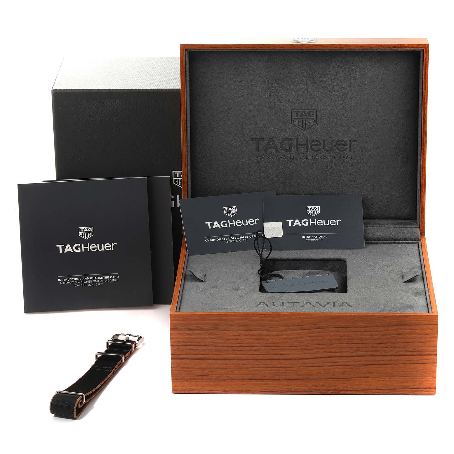 The image shows a Tag Heuer Autavia 63464 Men's Stainless Steel Brown Dial 63464 Men's Stainless Steel Brown Dial watch box with manuals, a watch strap, and tags, taken from the front angle.