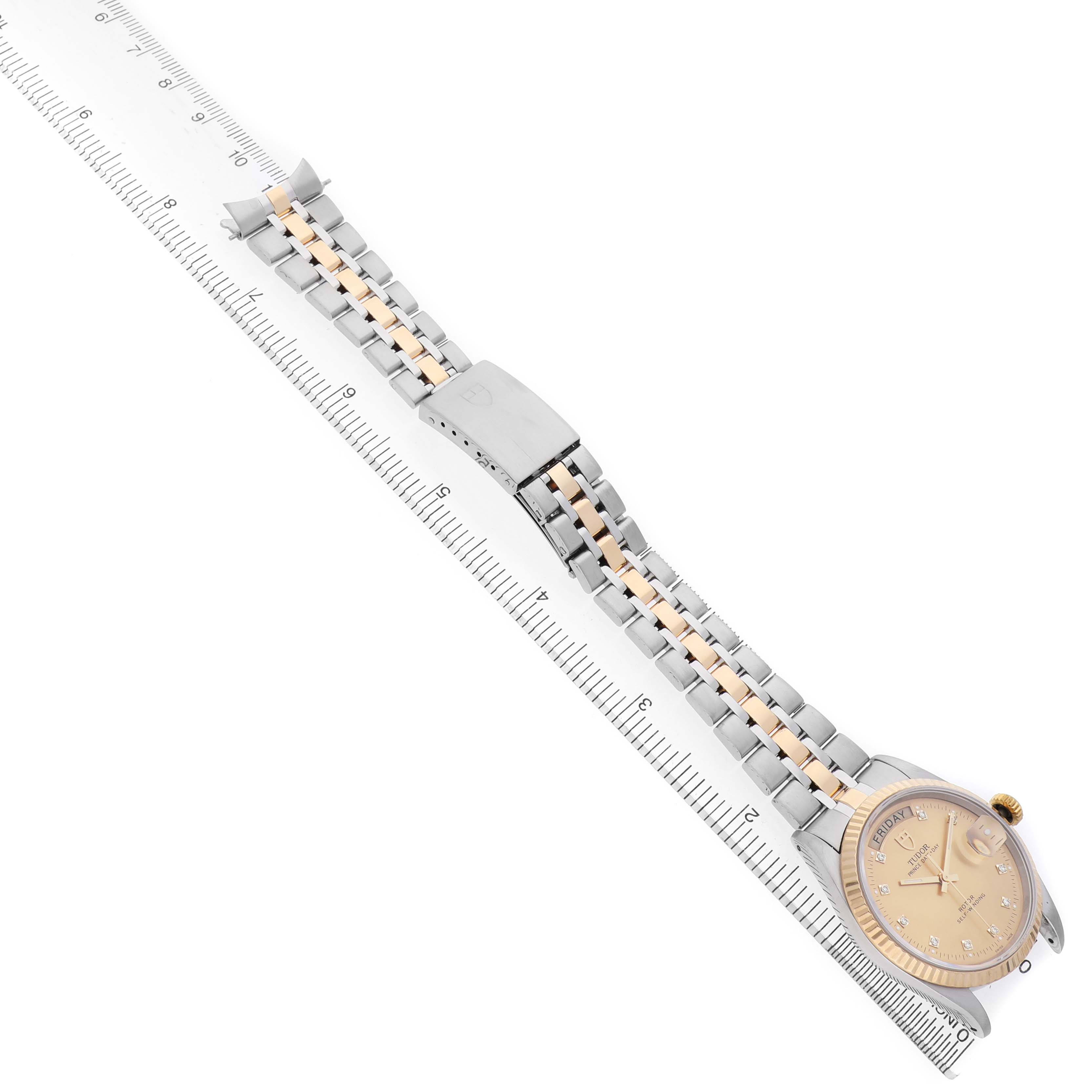 The Tudor Prince M76213 Men's Steel and Gold (two tone) Champagne Dial watch is shown from a top-down angle, displaying its full face, bracelet, and clasp alongside a ruler for scale.