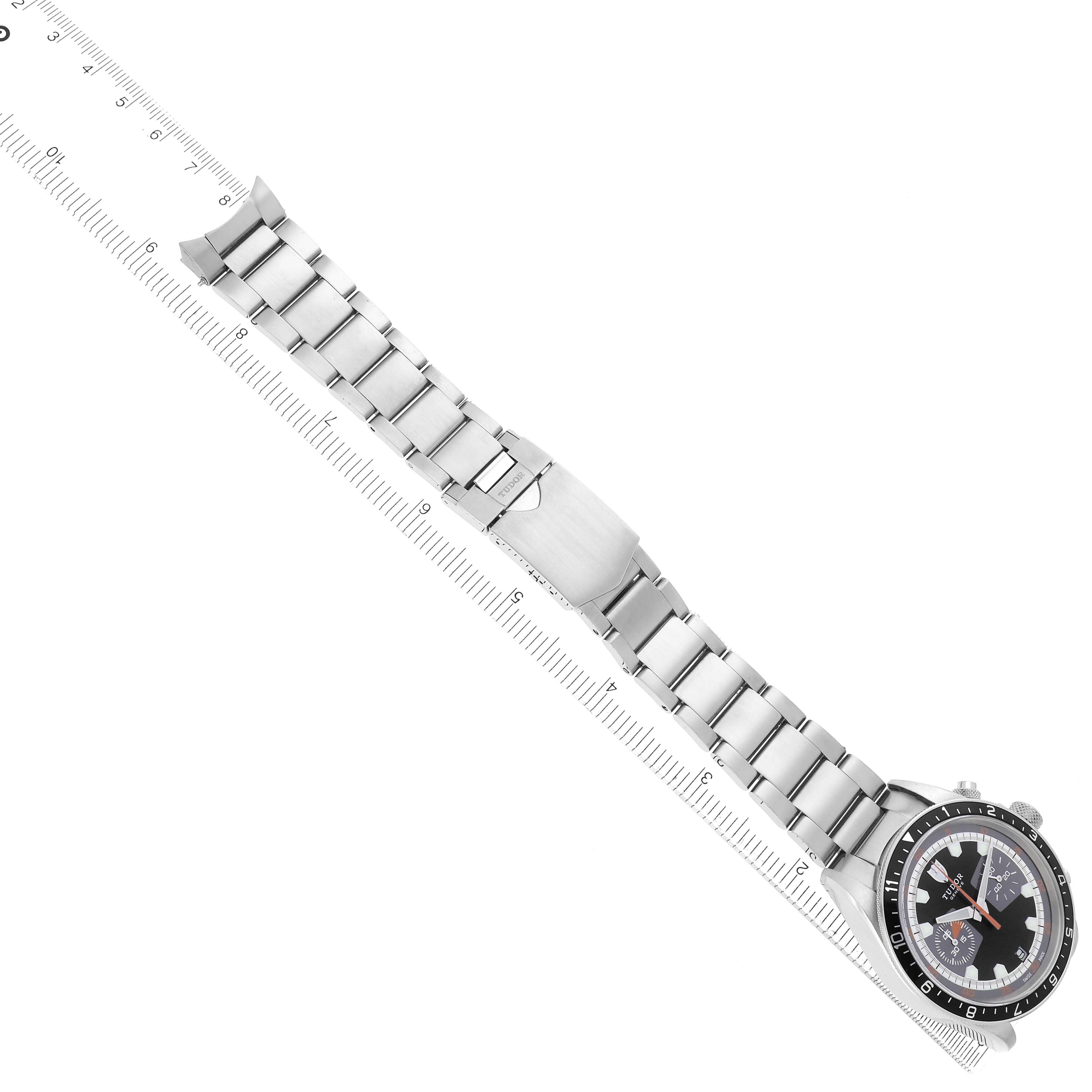 The Tudor Heritage Chrono 70330N-65740 is shown at a slight overhead angle, displaying the full watch and metal bracelet alongside a measuring ruler.