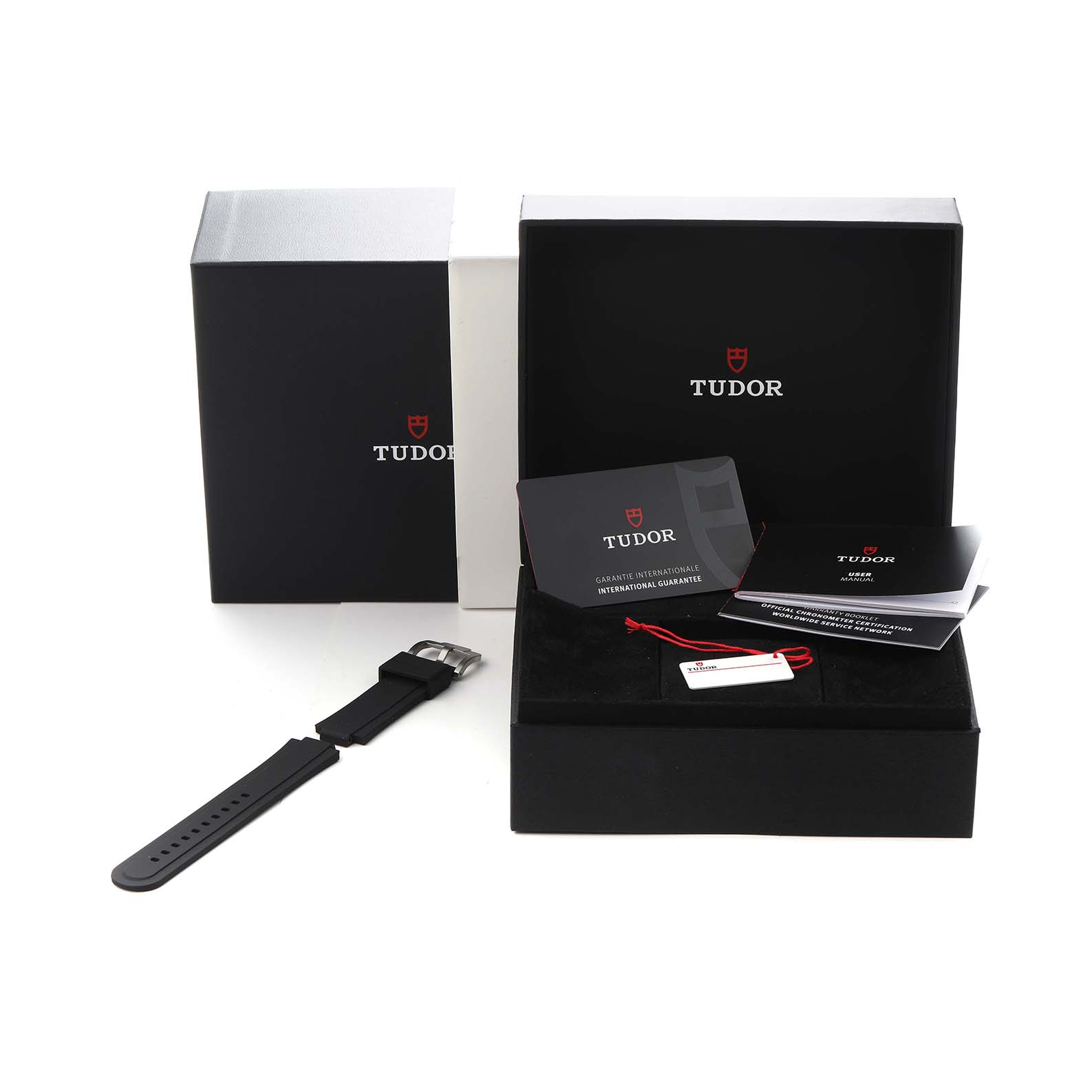 The image shows a Tudor Pelagos model M2543C1A7NU-0001 with its box, international guarantee card, booklets, and a black strap laid out beside the packaging.