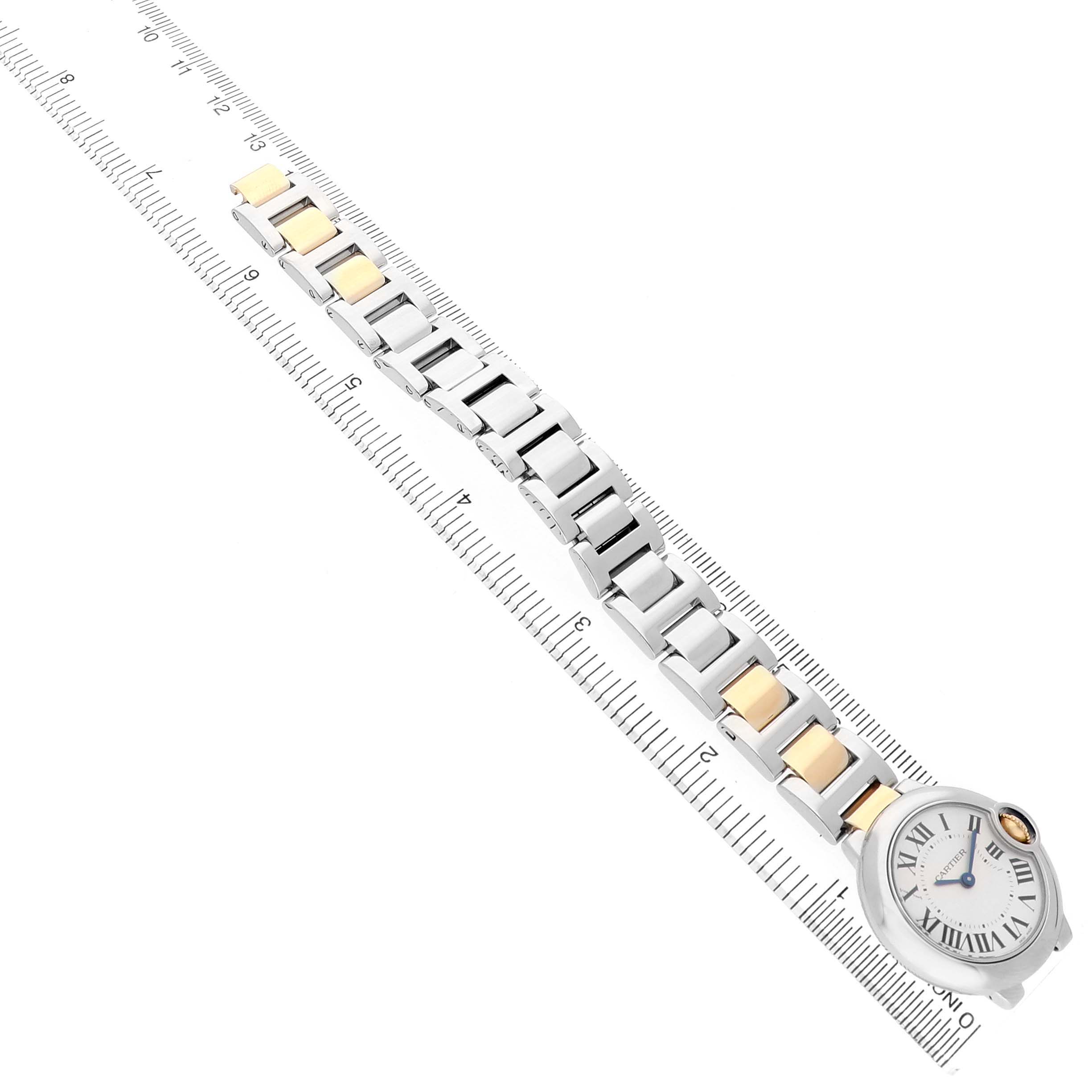 The Cartier Ballon Bleu W69007Z3 Women's Steel and Gold (two tone) Silver Dial watch is shown from a top view, highlighting its face and metal bracelet on a ruler for scale.