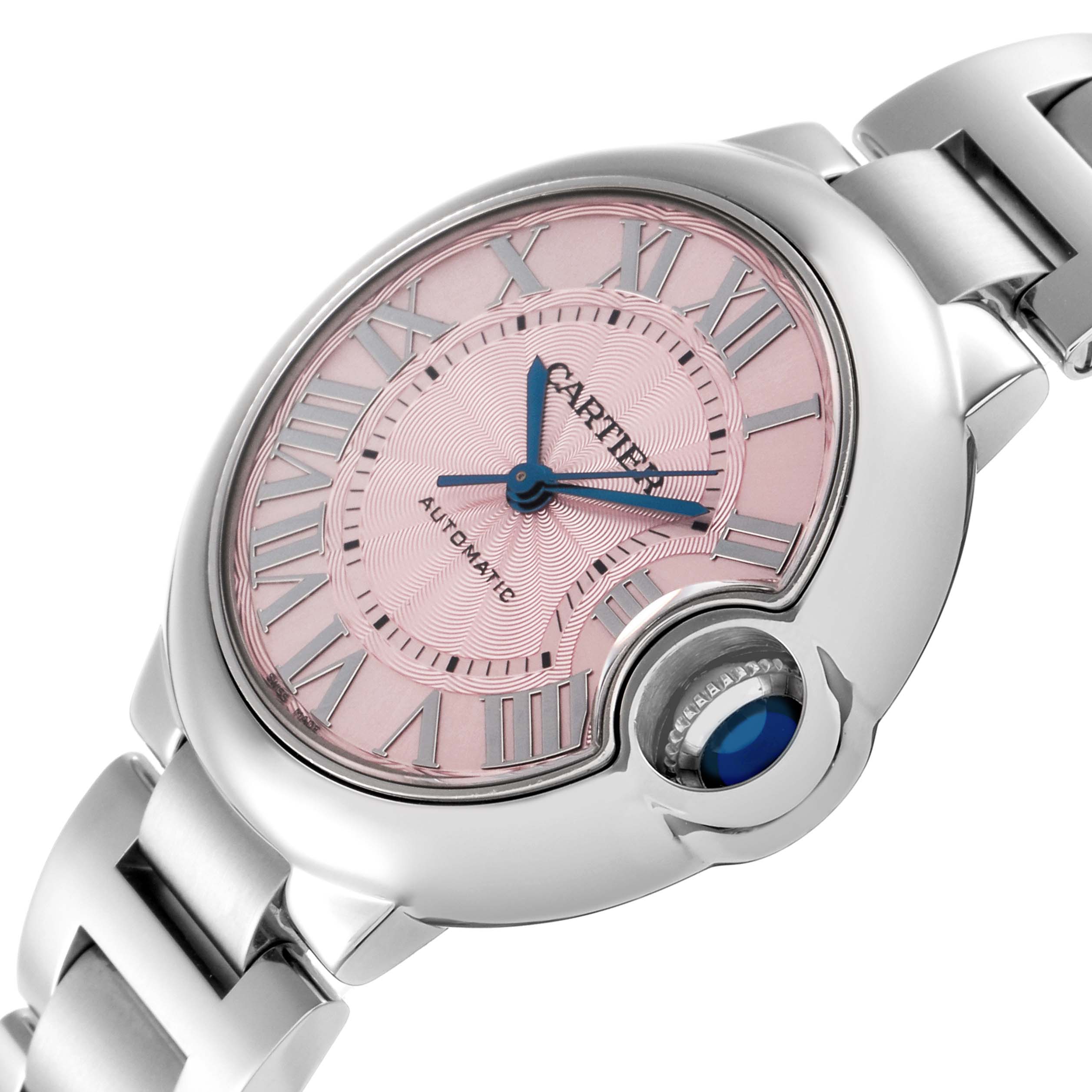 The Cartier Ballon Bleu W6920100 Women
s Stainless Steel Pink Dial W6920100 Women
s Stainless Steel Pink Dial watch is shown from a diagonal angle, highlighting the pink dial, blue hands, Roman numerals, and crown.