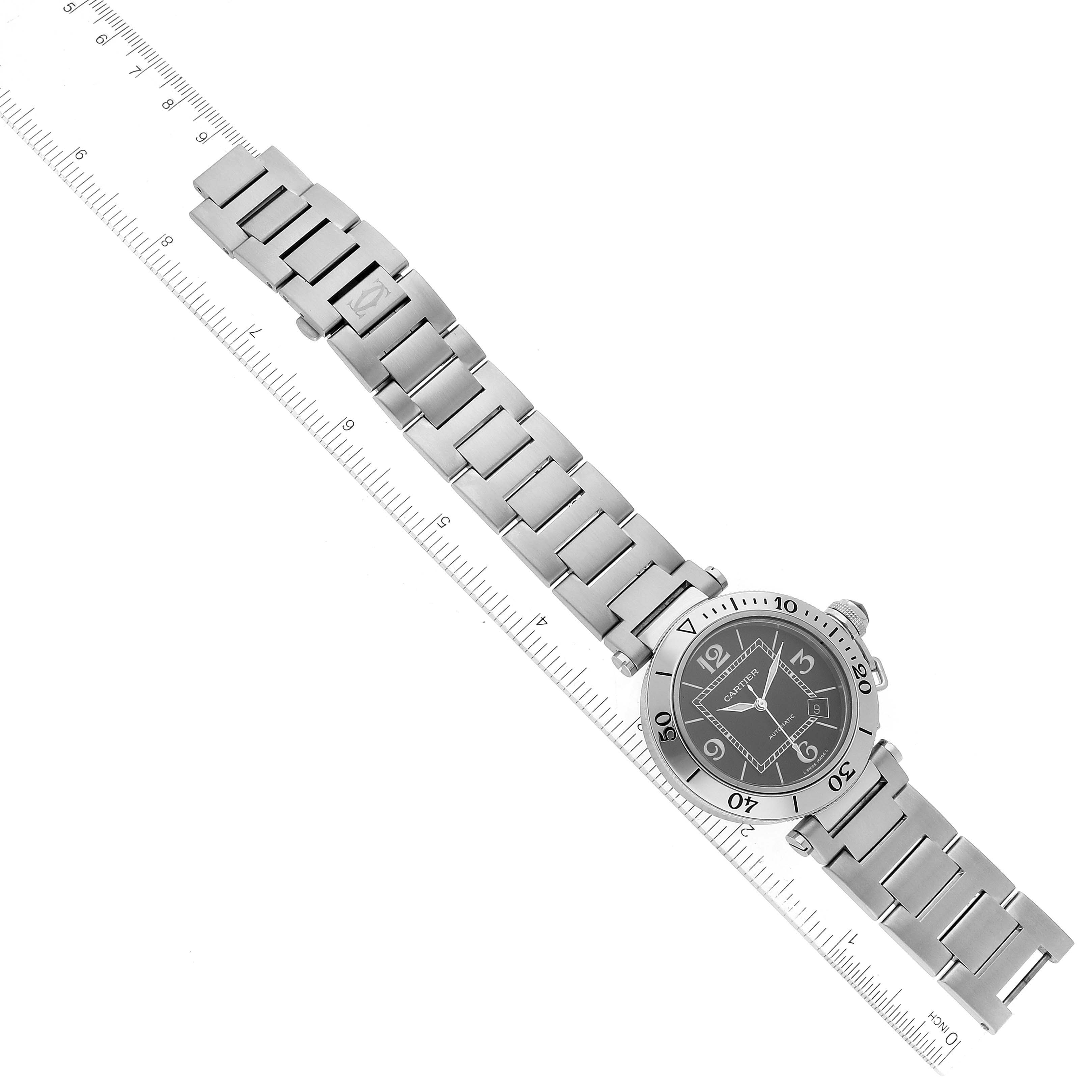 This image shows the entire Cartier Pasha W31077M7 Men's Stainless Steel Black Dial W31077M7 Men's Stainless Steel Black Dial watch, including the face and band, lying diagonally next to a ruler.