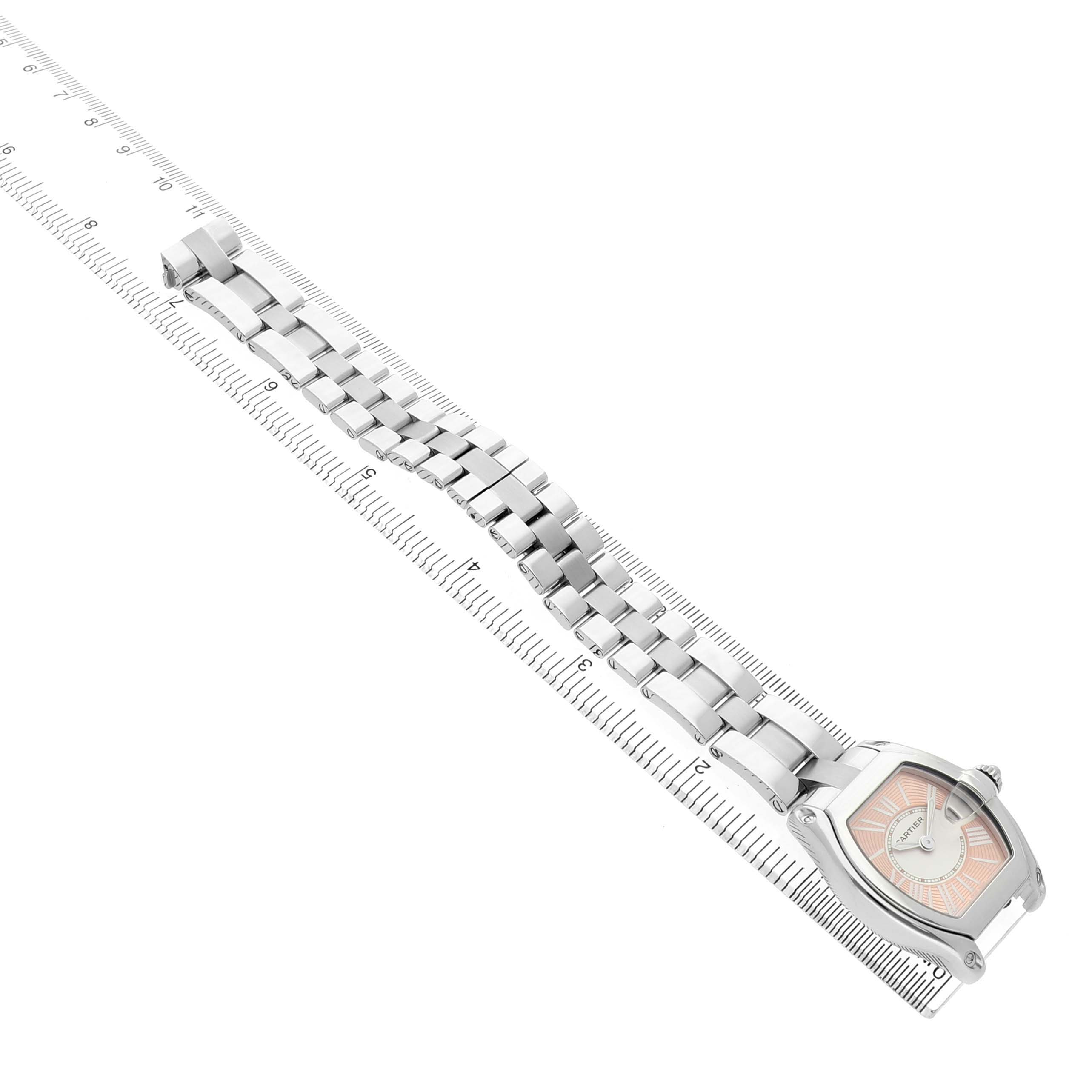 The Cartier Roadster W62054V3 Women's Stainless Steel Pink Dial watch is shown diagonally from an overhead angle, displaying the bracelet alongside a ruler for scale.