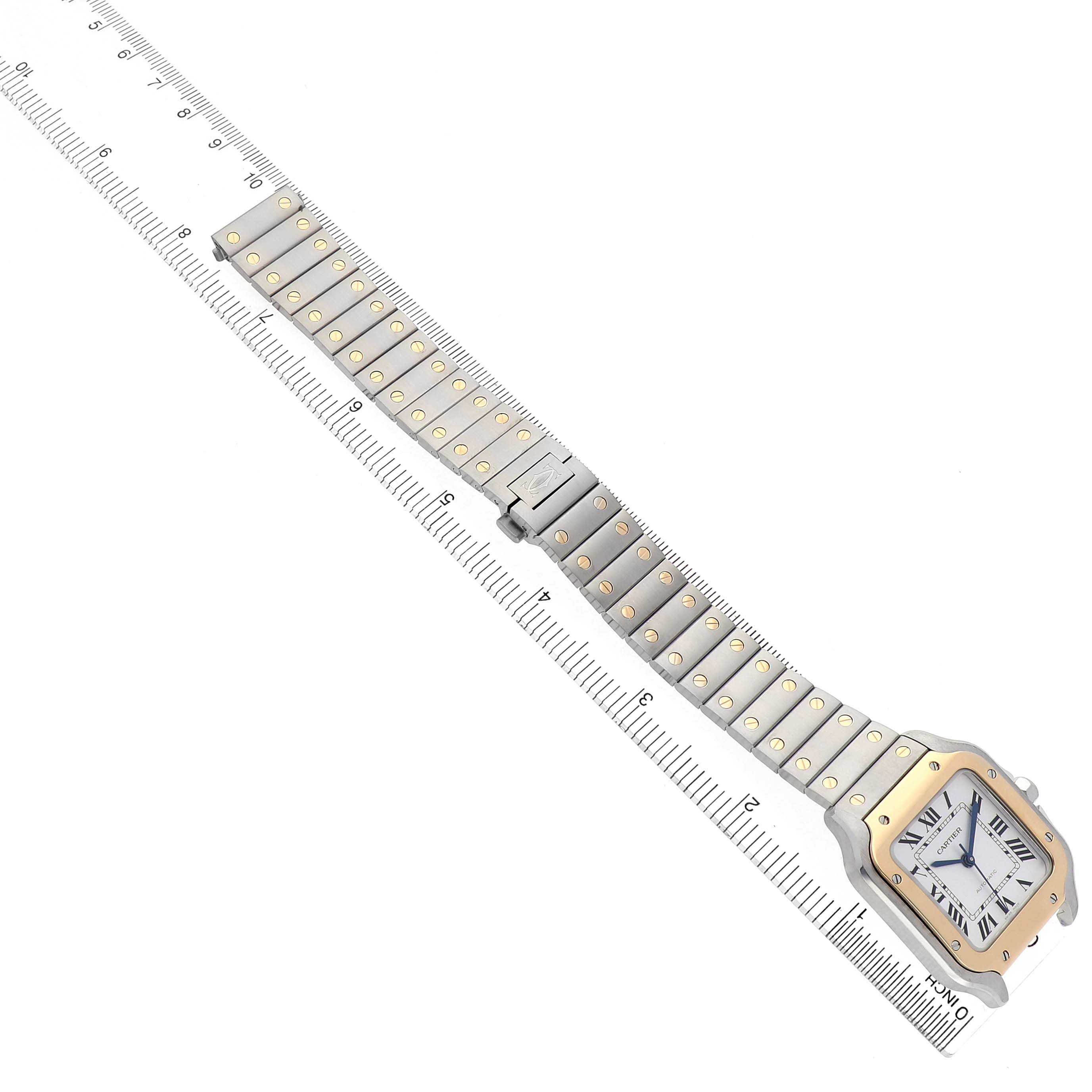 The Cartier Santos W2SA0016 Men's Stainless Steel Silver Dial watch is shown diagonally with its face and full metal bracelet visible alongside a ruler.