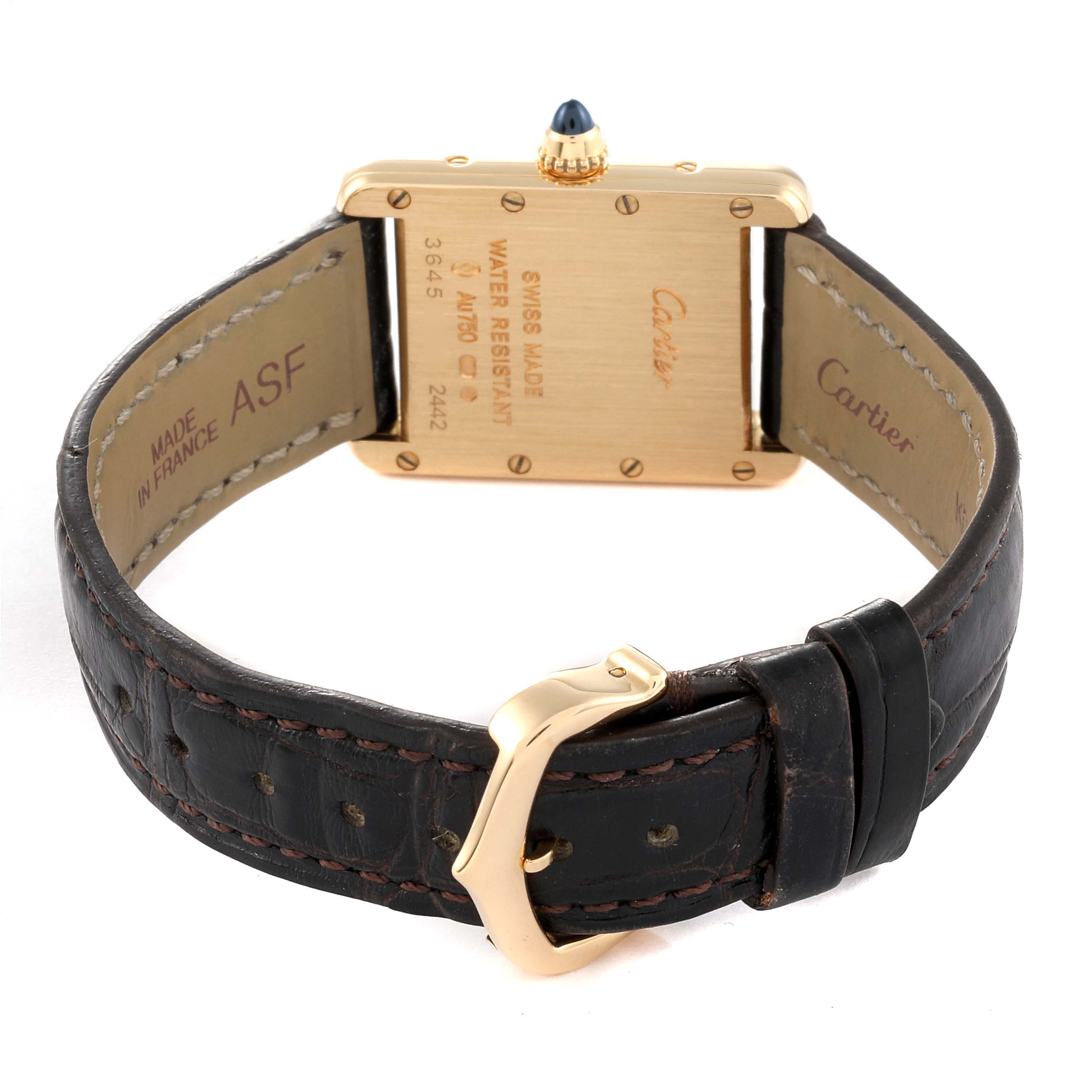 The image shows the back of a Tank Louis Cartier watch, displaying its gold case, markings, and leather strap with a gold buckle.