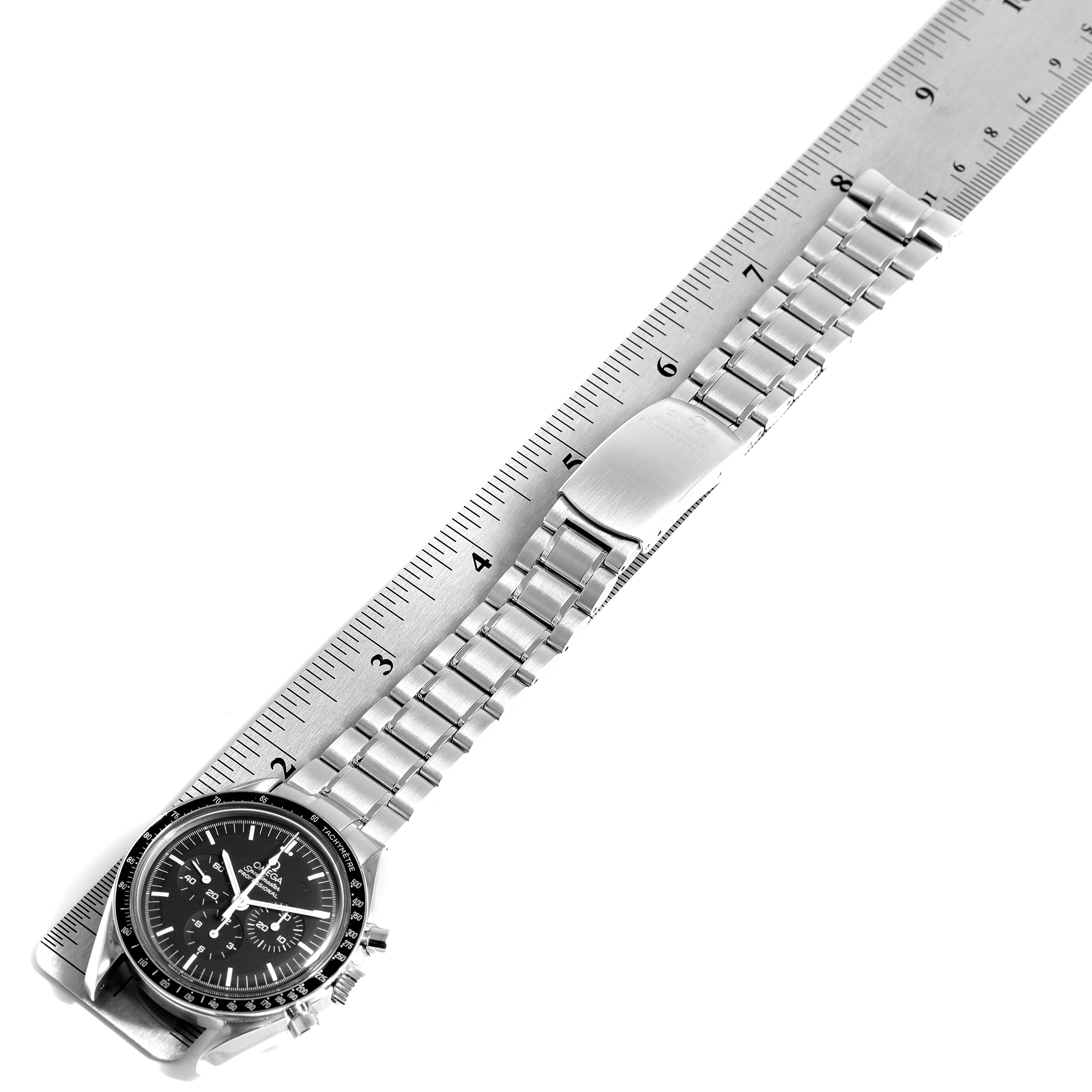 The image shows an Omega Speedmaster 3570.50.00 Men
s Stainless Steel Black Dial 3570.50.00 Men
s Stainless Steel Black Dial watch placed diagonally on a ruler, highlighting its metal band and clasp.