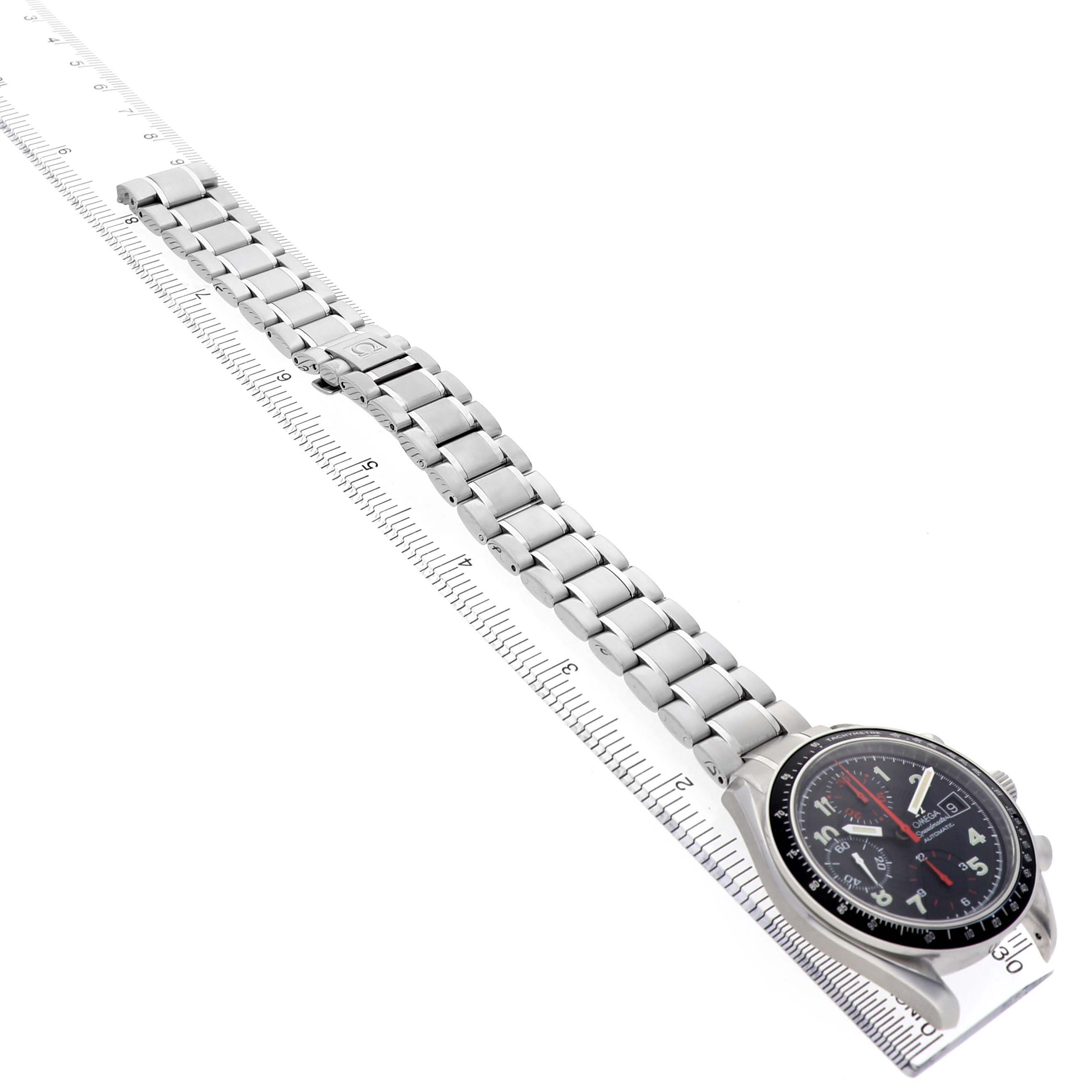 The Omega Speedmaster 3813.53.26 Men's Stainless Steel Black Dial watch is shown from a side angle, displaying the bracelet and face along a ruler for scale.