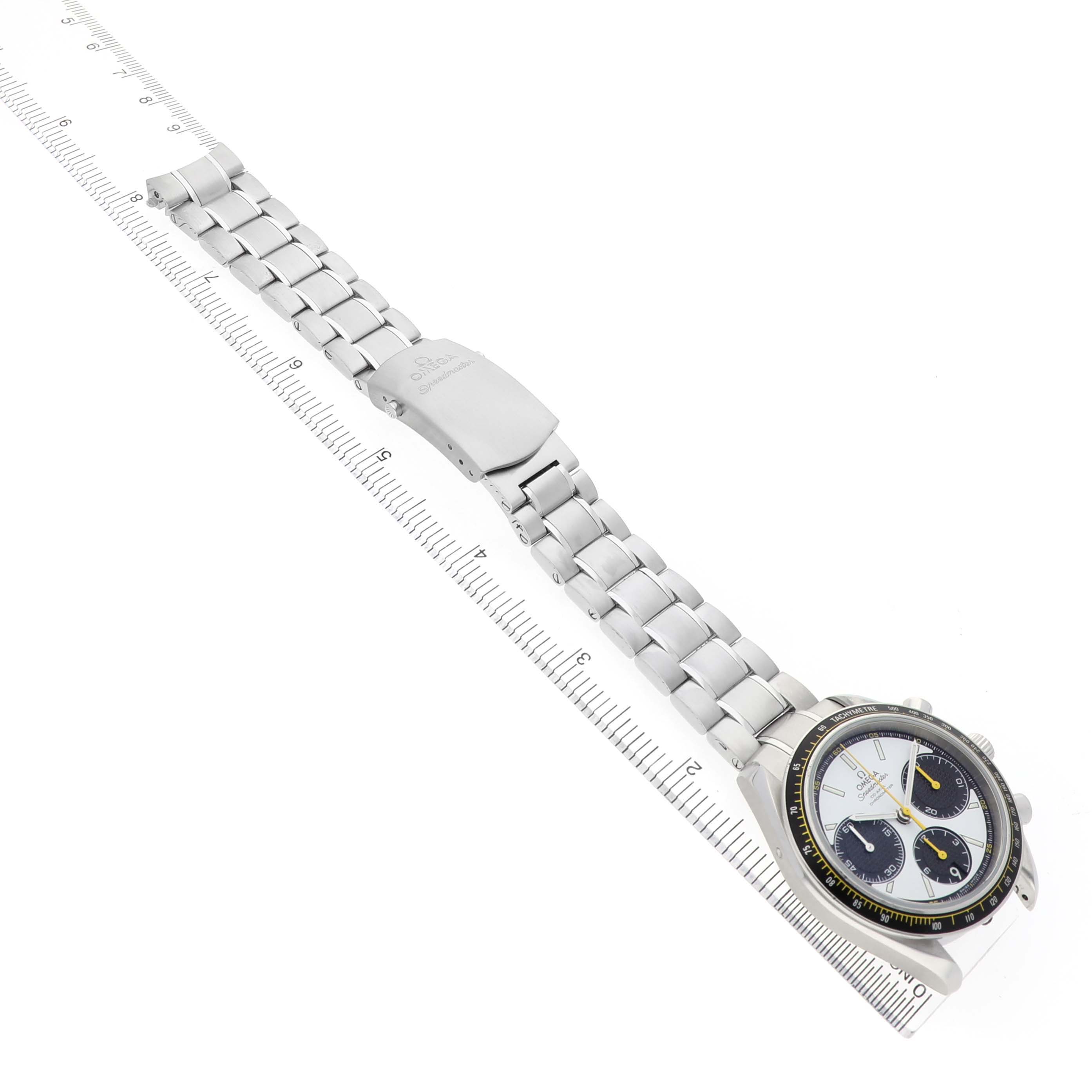 The Omega Speedmaster 326.30.40.50.04.001 Men's Stainless Steel White Dial watch is shown at an angle highlighting its face, bezel, and metal bracelet, placed on a ruler.