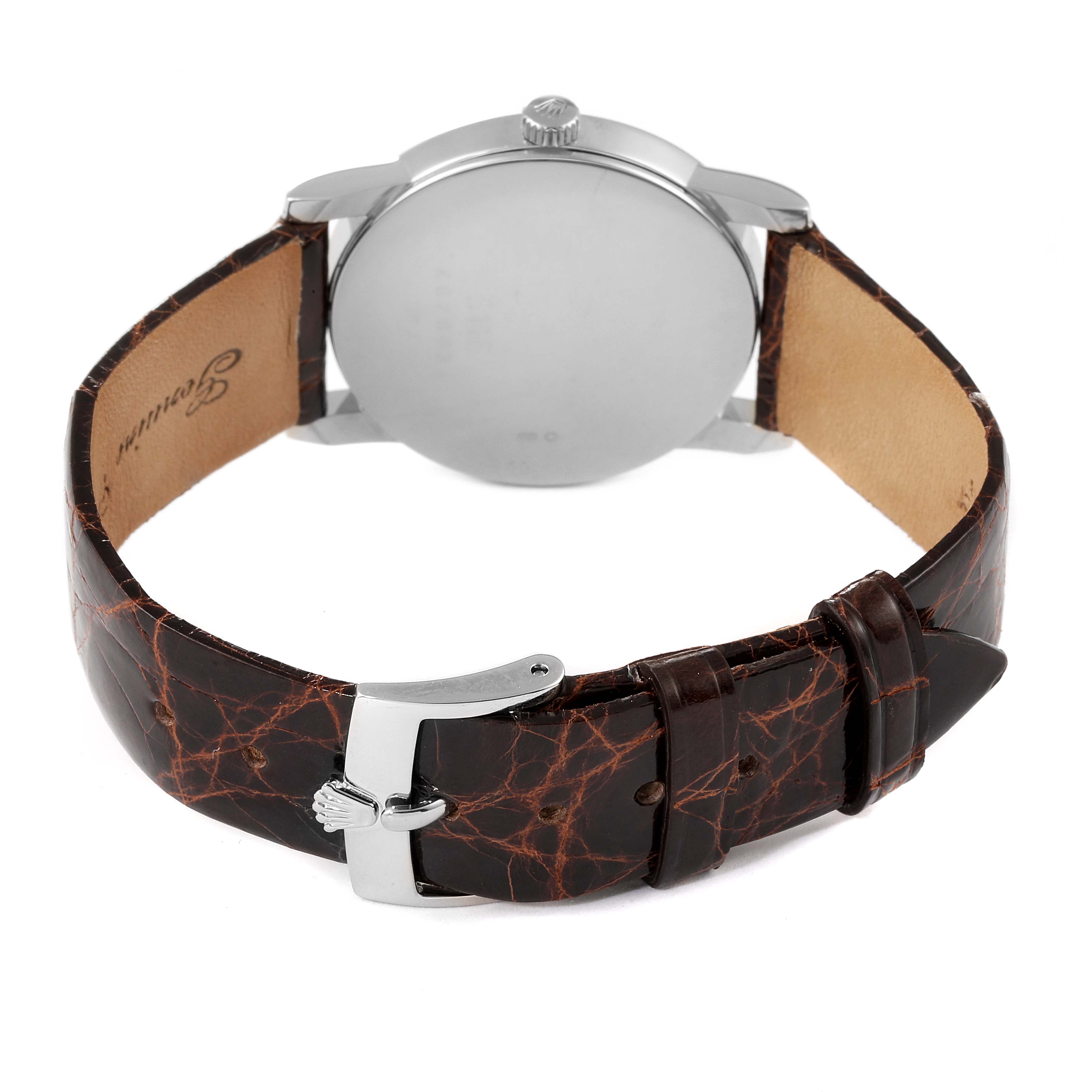 The image shows the back view of a Rolex Cellini 5116 Men's White Gold Black Dial 5116 Men's White Gold Black Dial watch, featuring its case, crown, and brown leather strap with a clasp.