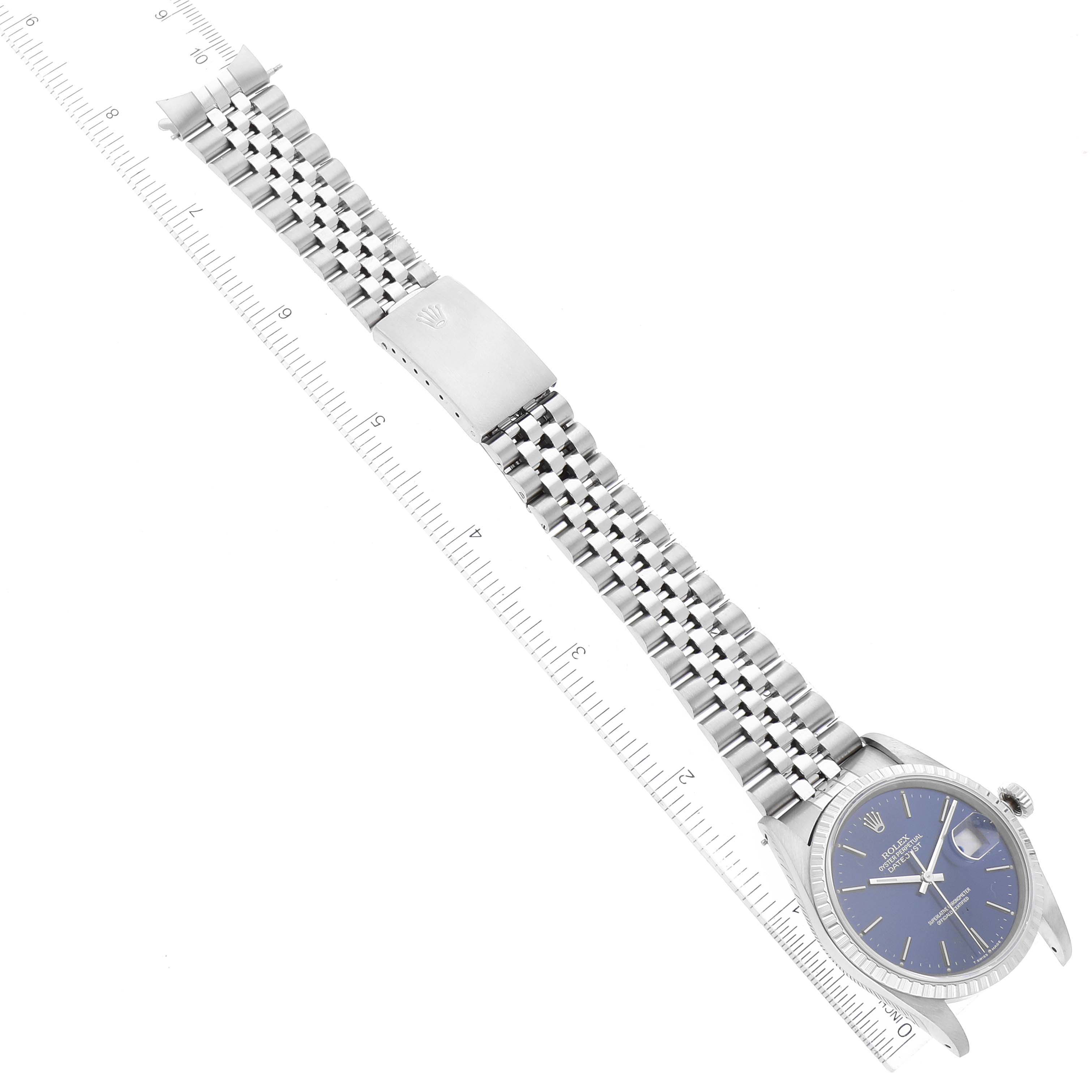 The image shows a top view of a Rolex Datejust 16220 Men's Stainless Steel Blue Dial 16220 Men's Stainless Steel Blue Dial model, featuring its dial, bezel, and bracelet laid out flat alongside a ruler.