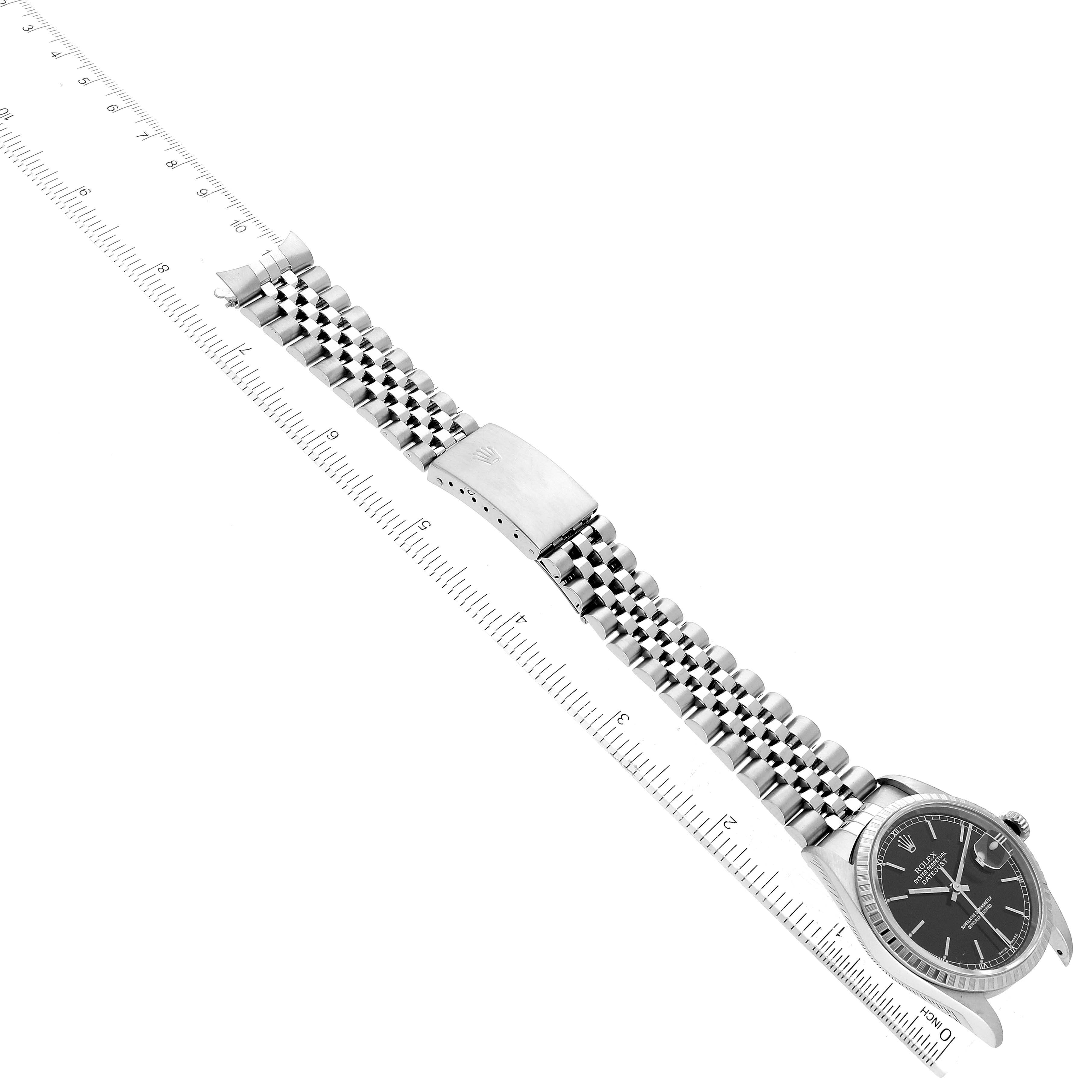 The Rolex Datejust 16220 Men's Stainless Steel Black Dial 16220 Men's Stainless Steel Black Dial watch is shown from a top-down angle with the face, bracelet, and clasp visible next to a measuring ruler.
