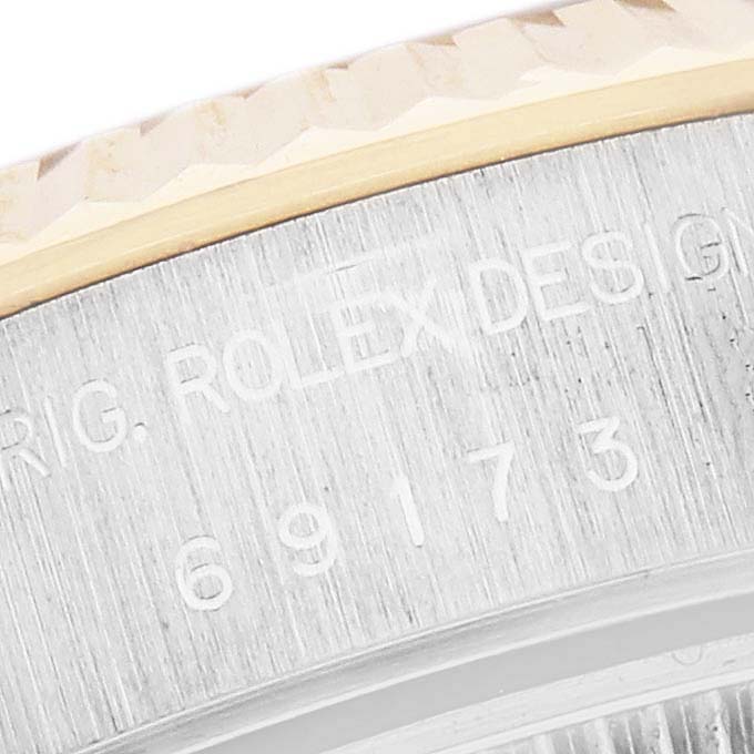 The image shows a close-up of the engraved case side of a Rolex Datejust 69173 Women
s Steel and Gold (two tone) Mother of Pearl Dial 69173 Women
s Steel and Gold (two tone) Mother of Pearl Dial, focusing on the serial number and fluted bezel.