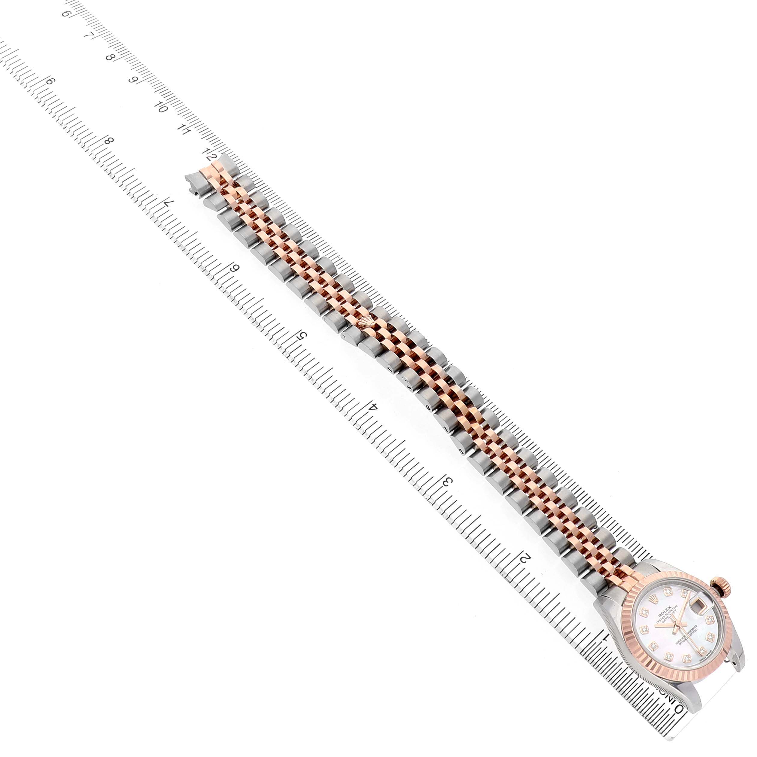 The Rolex Datejust 179171 Women's Stainless Steel Mother of Pearl Dial is shown from a top view, highlighting the watch face, bezel, and bracelet against a ruler for scale.