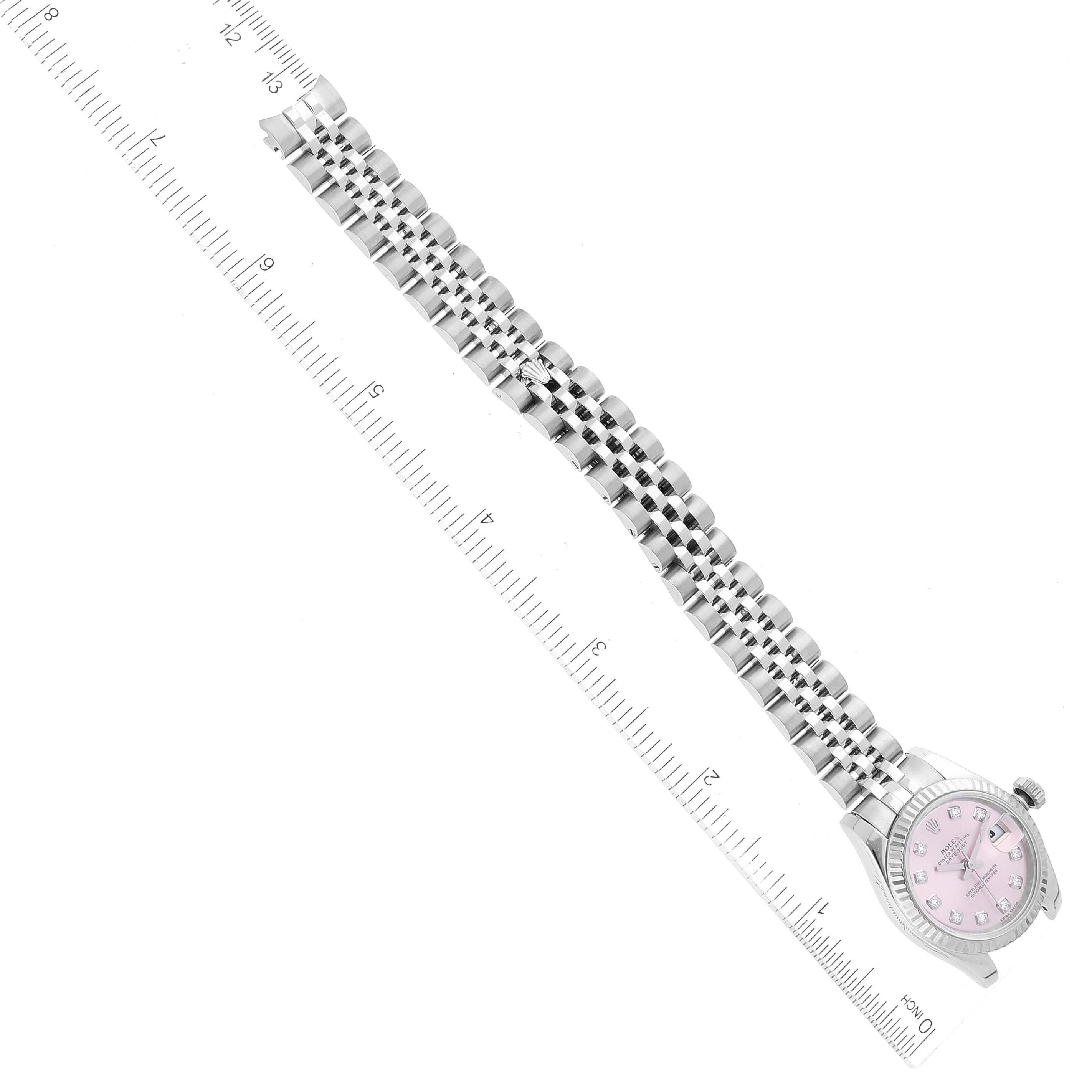 This image shows a Rolex Datejust 179174 Women's Stainless Steel Pink Dial 179174 Women's Stainless Steel Pink Dial watch laid flat with its band extended next to a ruler for measurement.