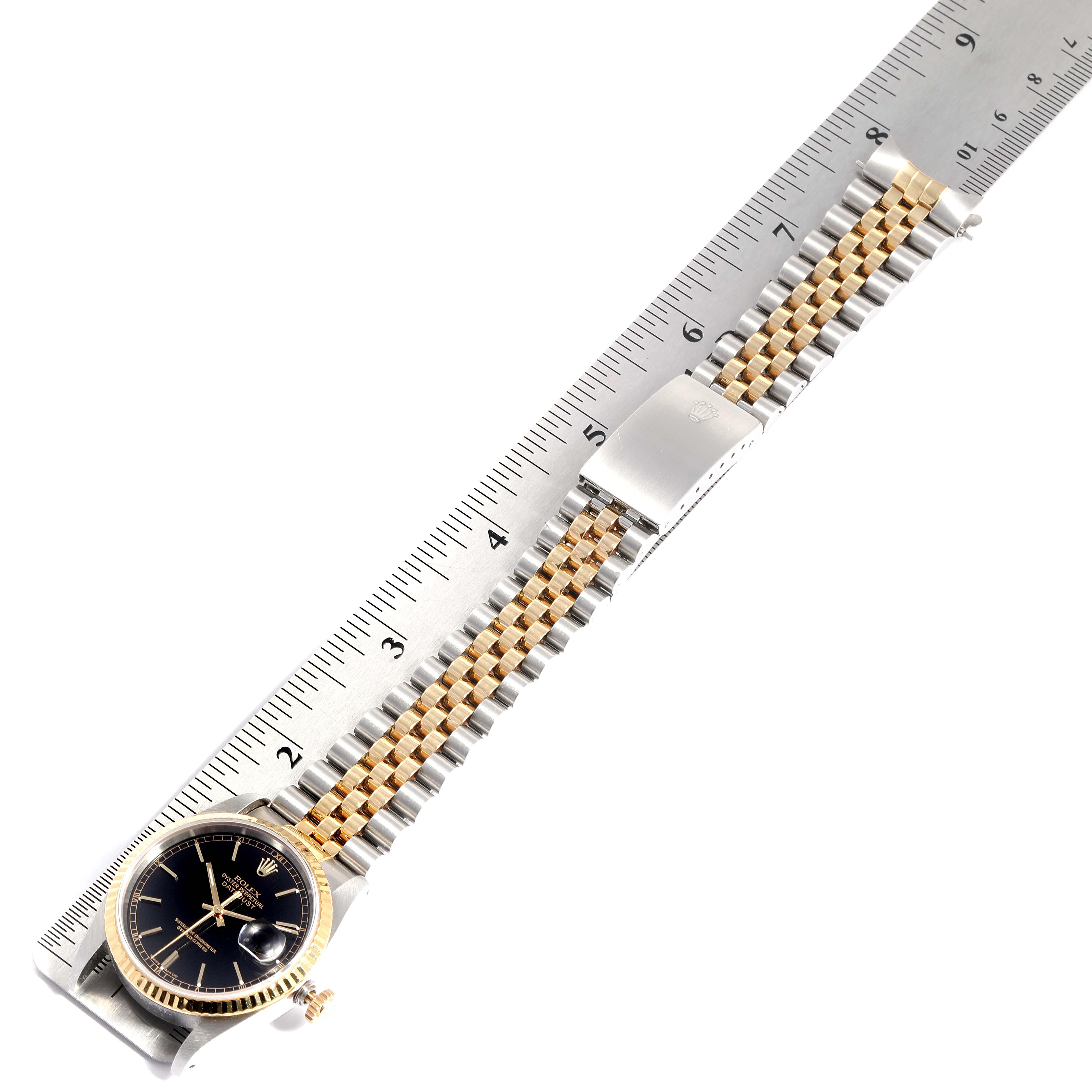 The image shows a Rolex Datejust 16233 Men's Steel and Gold (two tone) Black Dial 16233 Men's Steel and Gold (two tone) Black Dial watch laid flat on a ruler with its band fully extended.