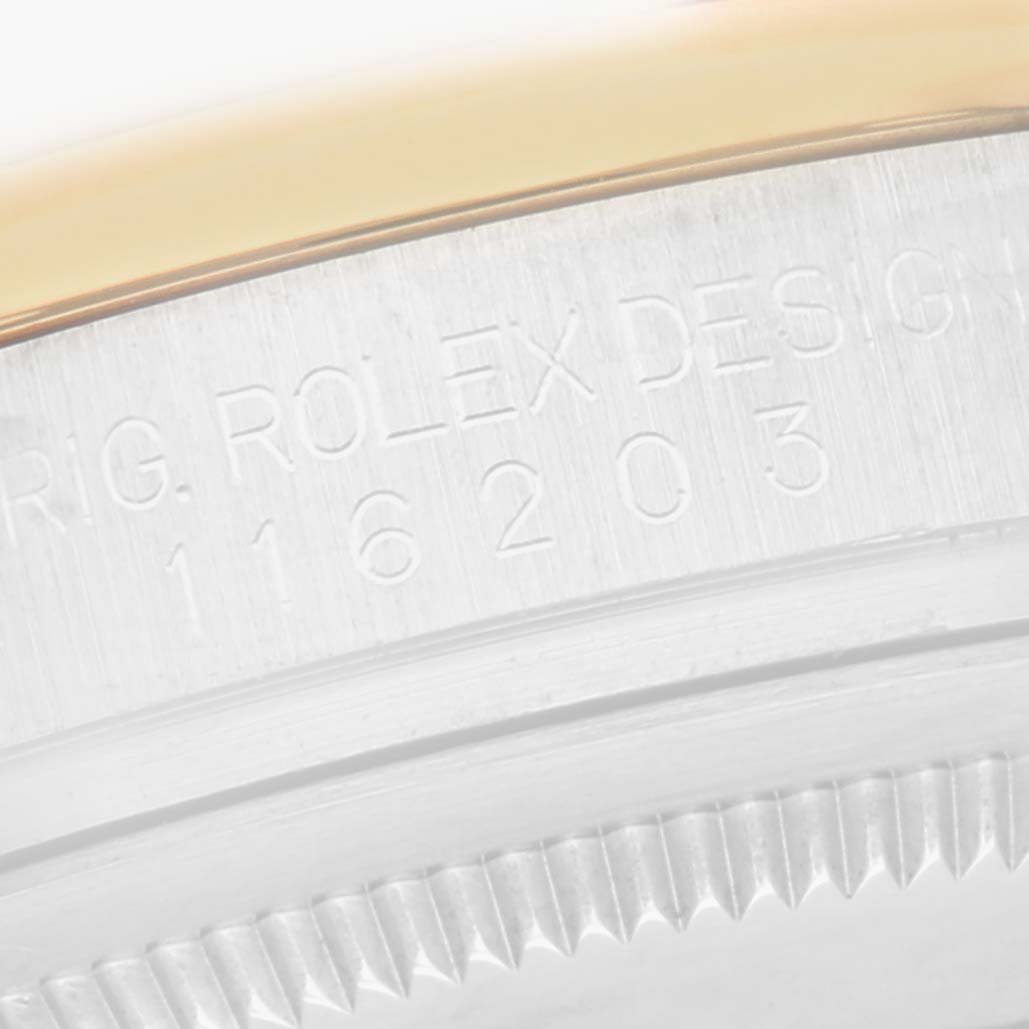 The image shows a close-up of a Rolex Datejust 116203 Men
s Steel and Gold (two tone) Champagne Dial 116203 Men
s Steel and Gold (two tone) Champagne Dial model
s outer case and fluted bezel, featuring engraved details.