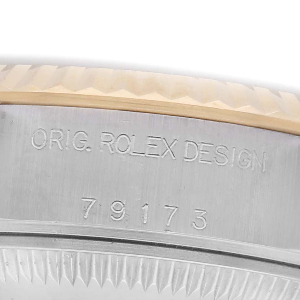 The image shows a close-up of the side of a Rolex Datejust 79173 Women
s Steel and Gold (two tone) White Dial 79173 Women
s Steel and Gold (two tone) White Dial, highlighting the bezel and engraved design numbers.
