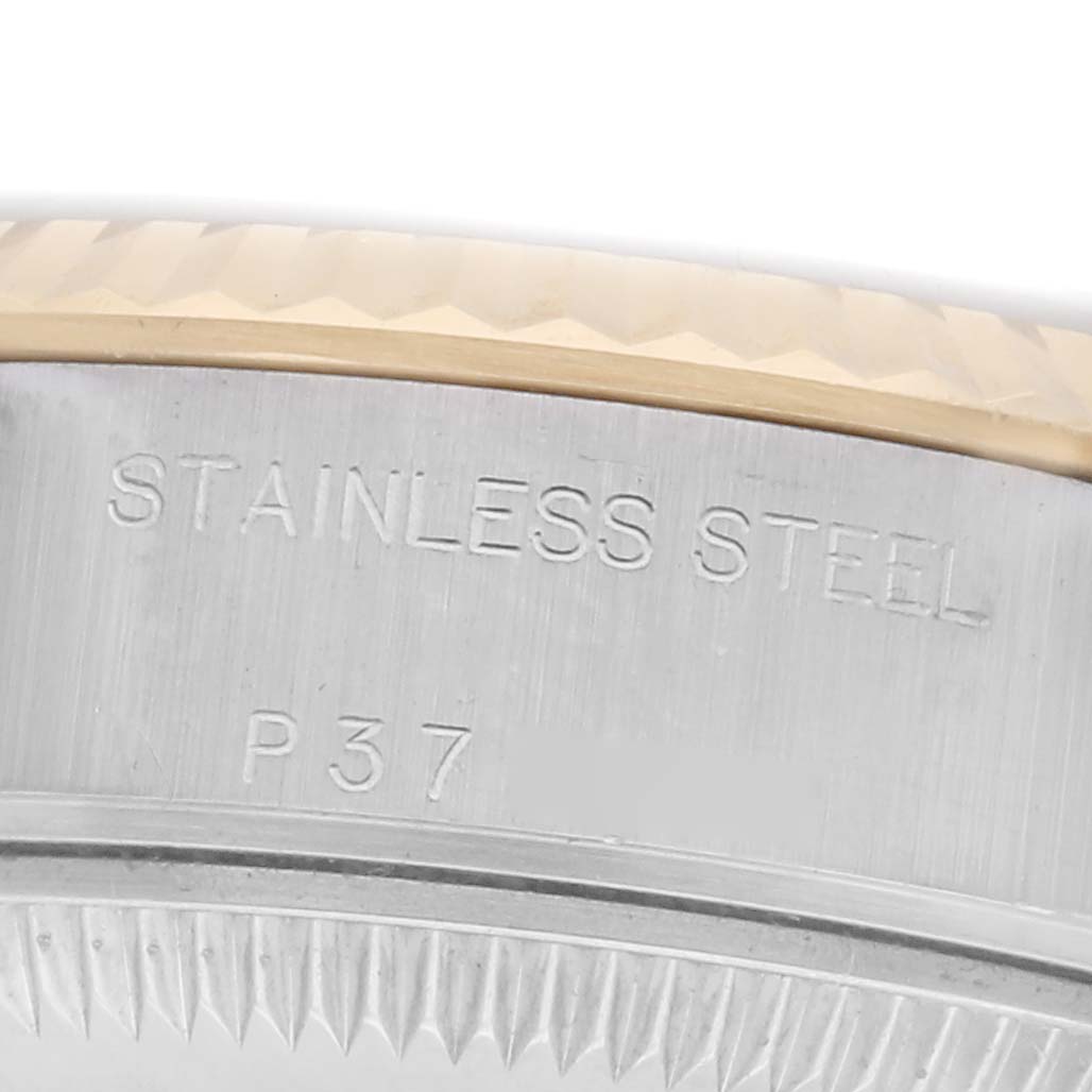 The image shows a close-up of the Rolex Datejust 79173 Women
s Steel and Gold (two tone) White Dial 79173 Women
s Steel and Gold (two tone) White Dial
s stainless steel and engraved bezel with fluted edges.