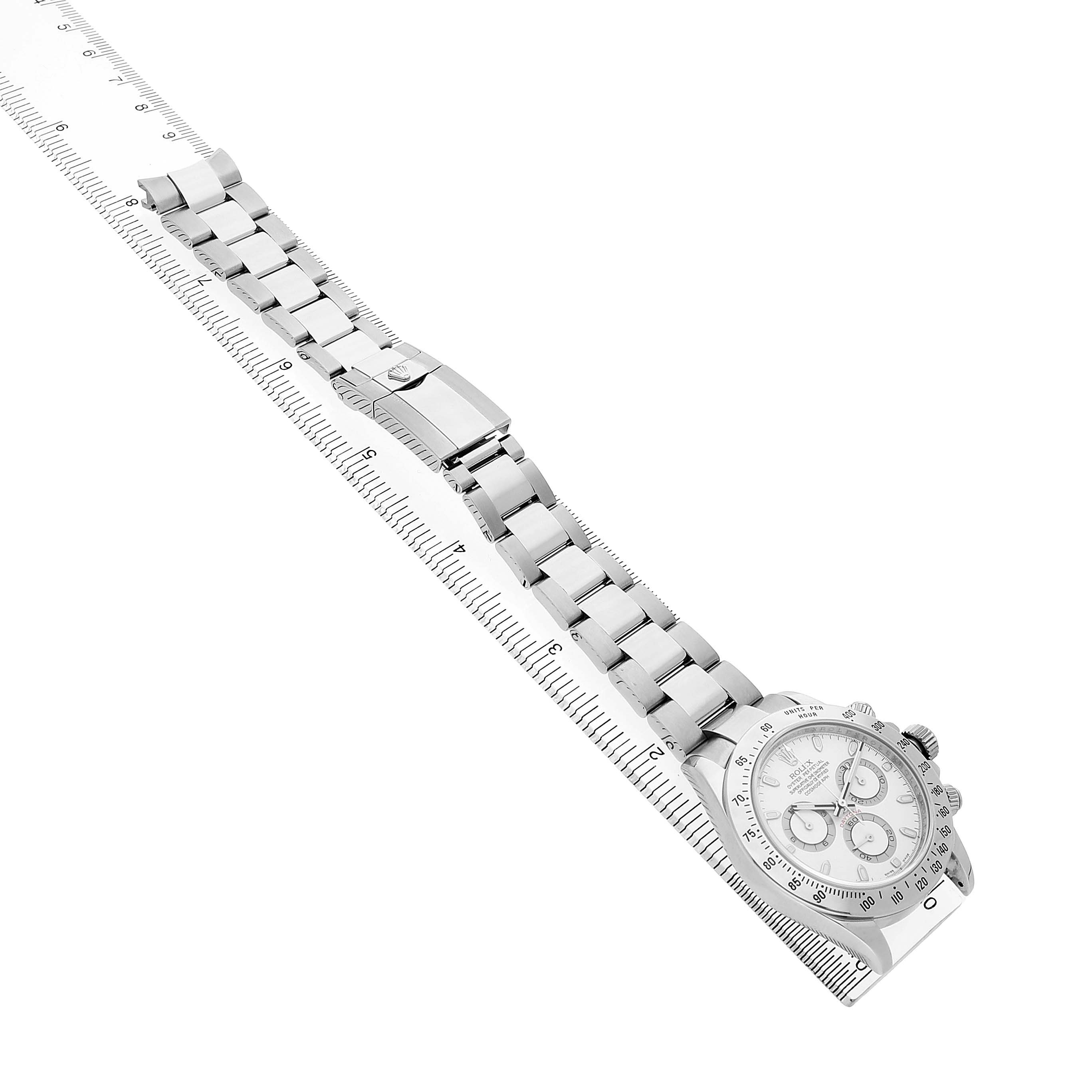 The image shows a Rolex Daytona 116520 Men's Stainless Steel White Dial watch angled diagonally with a focus on the bracelet and face, alongside a ruler.