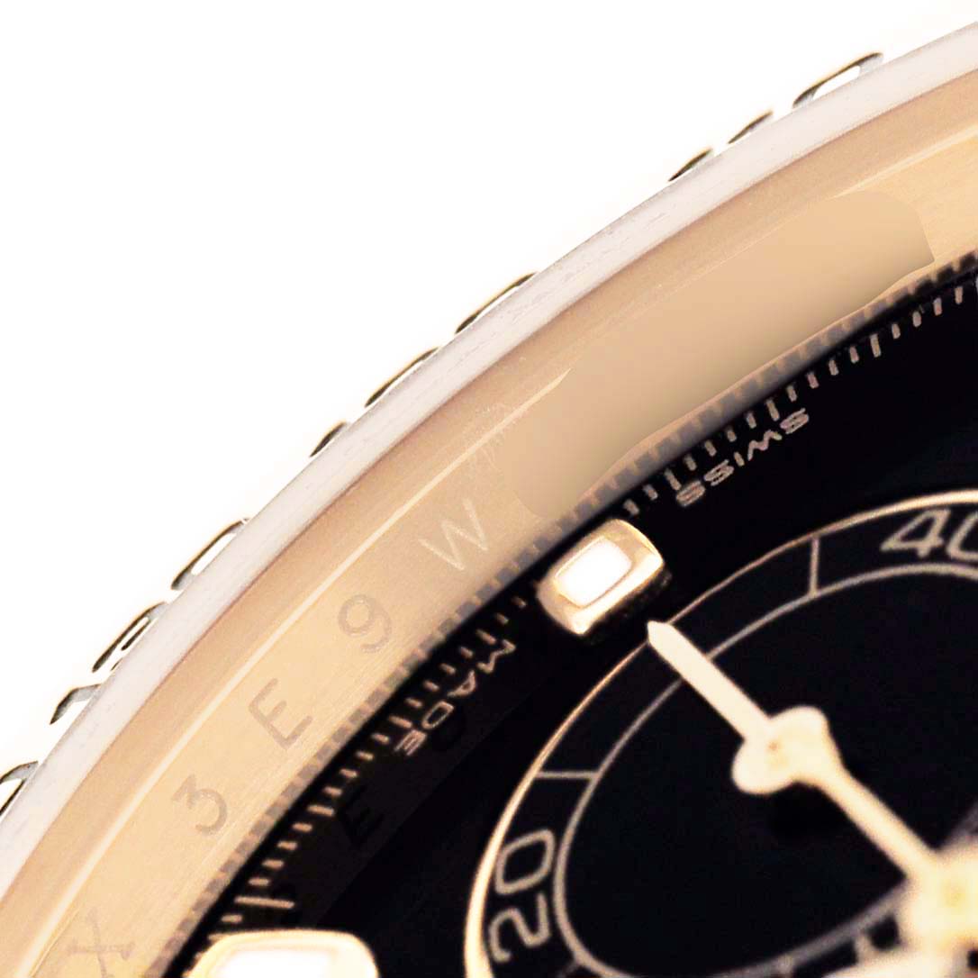 The image shows a close-up angle of the Rolex Daytona 116508 Men's Yellow Gold Black Dial's bezel, part of the dial, and a hand marker.