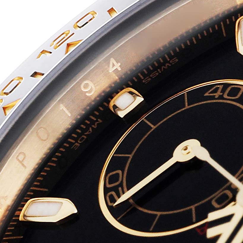 This close-up of a Rolex Daytona 116518 Men's Yellow Gold Black Dial 116518 Men's Yellow Gold Black Dial watch shows part of the bezel, dial, and watch hands.