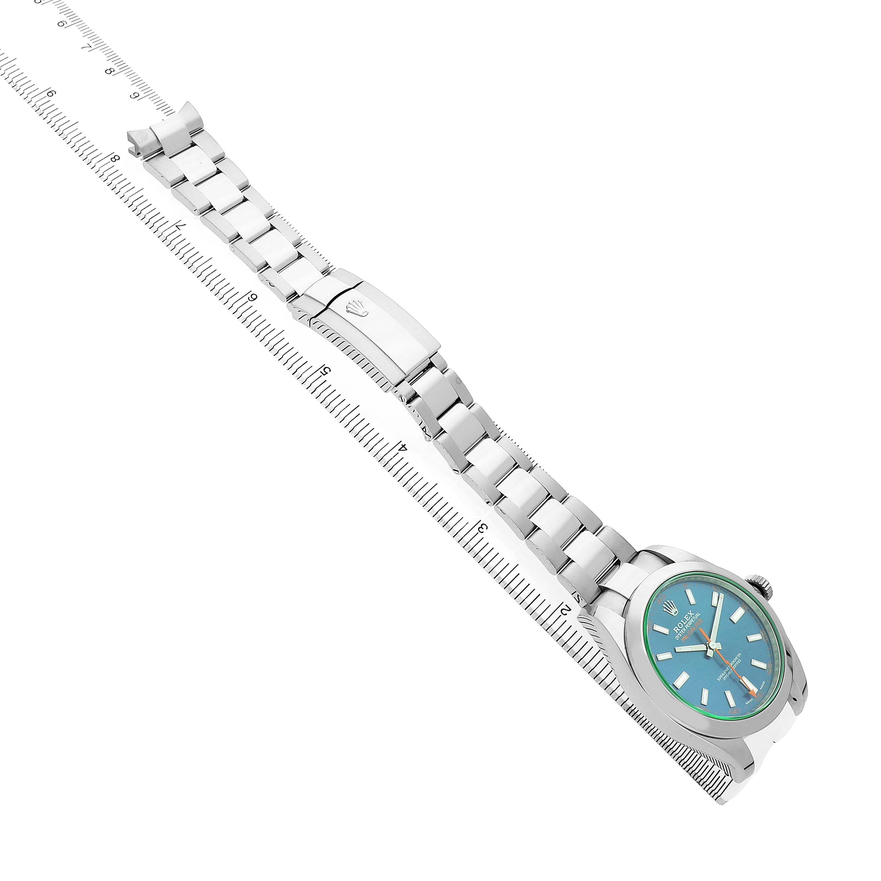 The Rolex Milgauss M116400GV Men's Stainless Steel Blue Dial watch is shown sideways with the full bracelet laid alongside a ruler, displaying its clasp and dial.