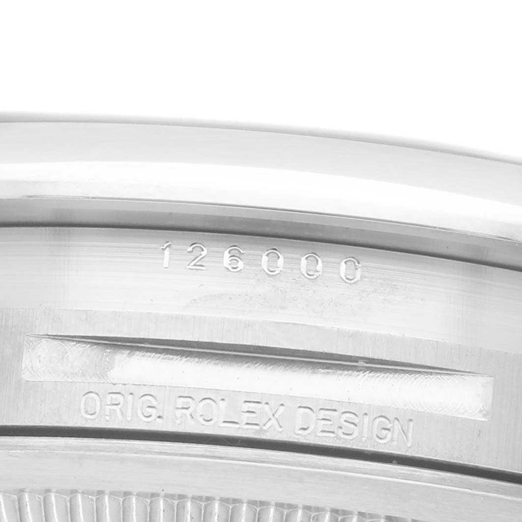 The image shows a close-up of the serial number engraving on the case back of a Rolex Oyster Perpetual M126000-0001 Men's Stainless Steel Silver Dial watch.