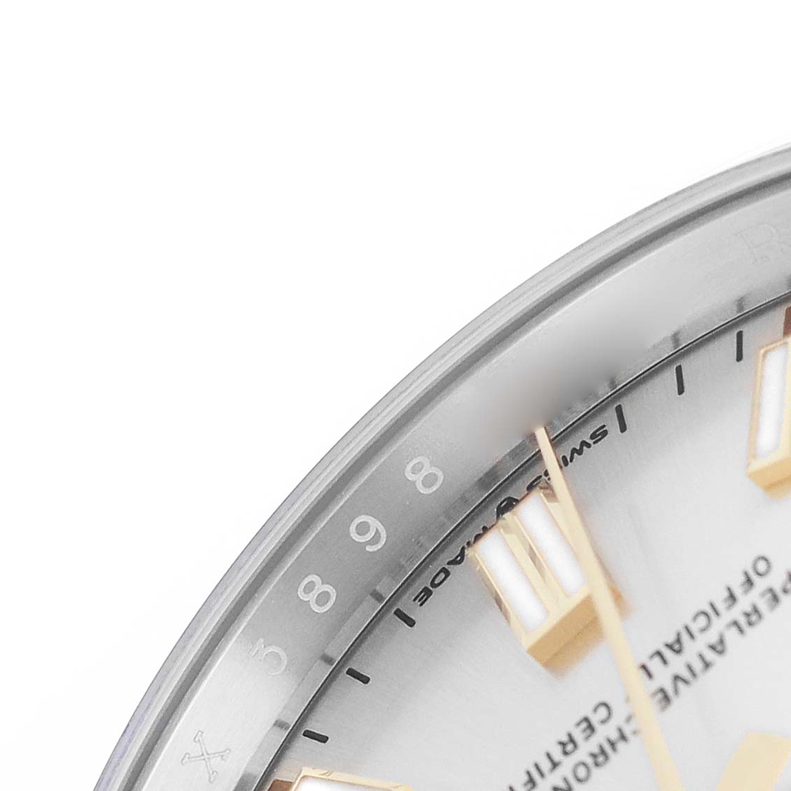 The image shows a close-up of the Rolex Oyster Perpetual M126000-0001 Men's Stainless Steel Silver Dial watch's dial and hour markers from an angled view.
