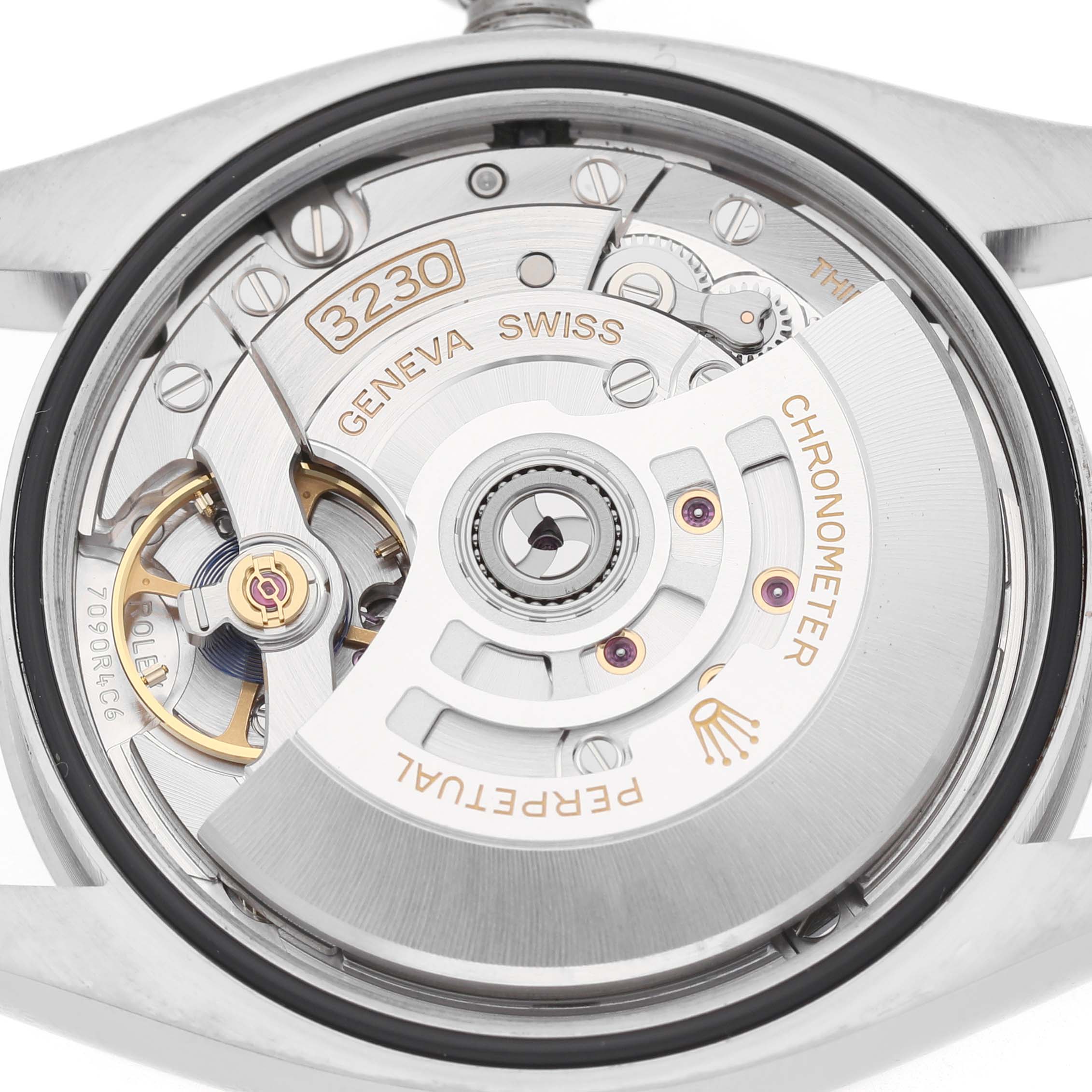The image shows the movement of a Rolex Oyster Perpetual M126000-0001 Men's Stainless Steel Silver Dial watch, viewed from the back, highlighting the rotor and gears.