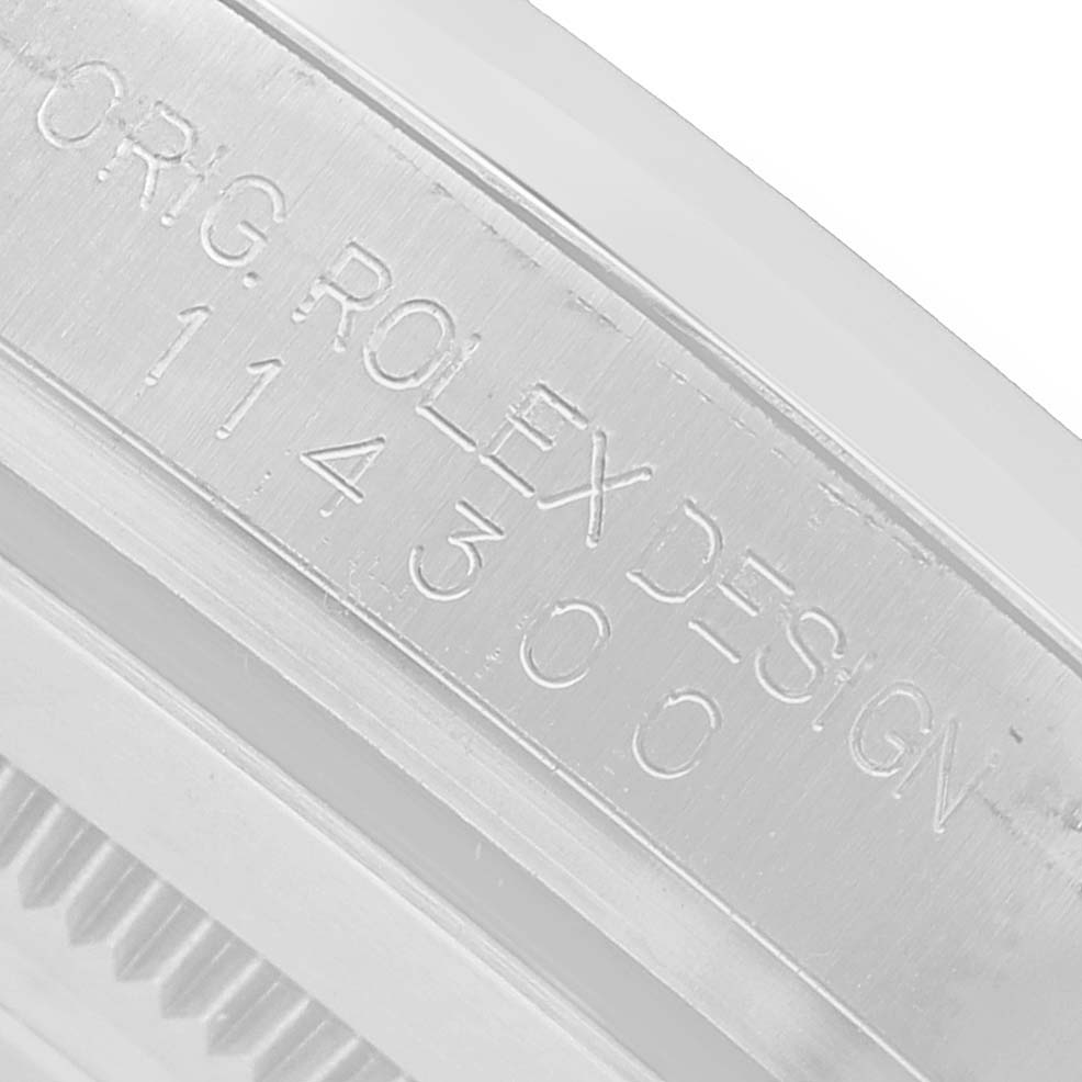 The image shows a close-up of the inner case engraving on a Rolex Oyster Perpetual 114300 Men's Stainless Steel Blue Dial watch.