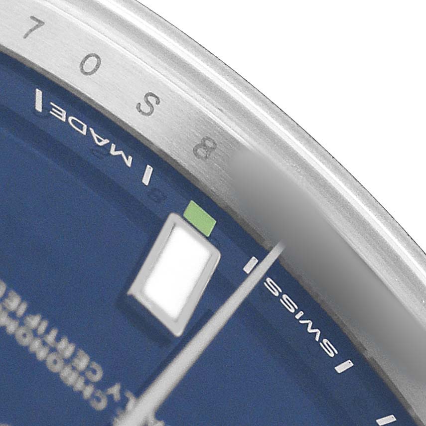 The image shows a close-up of the dial, bezel, and part of the face of a Rolex Oyster Perpetual 114300 Men's Stainless Steel Blue Dial watch, highlighting the minute marks.