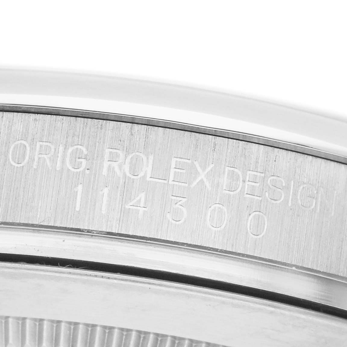 The image shows the side of the bezel of a Rolex Oyster Perpetual 114300 Men's Stainless Steel Purple Dial, featuring engraved text and model number.
