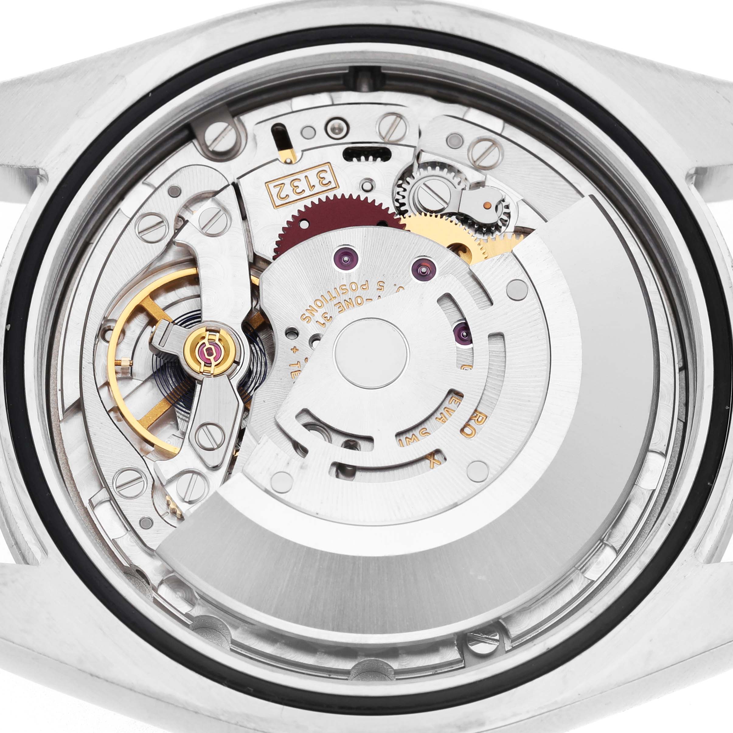 The image shows a close-up of the movement inside a Rolex Oyster Perpetual 114300 Men's Stainless Steel Purple Dial watch, highlighting gears and intricate components.