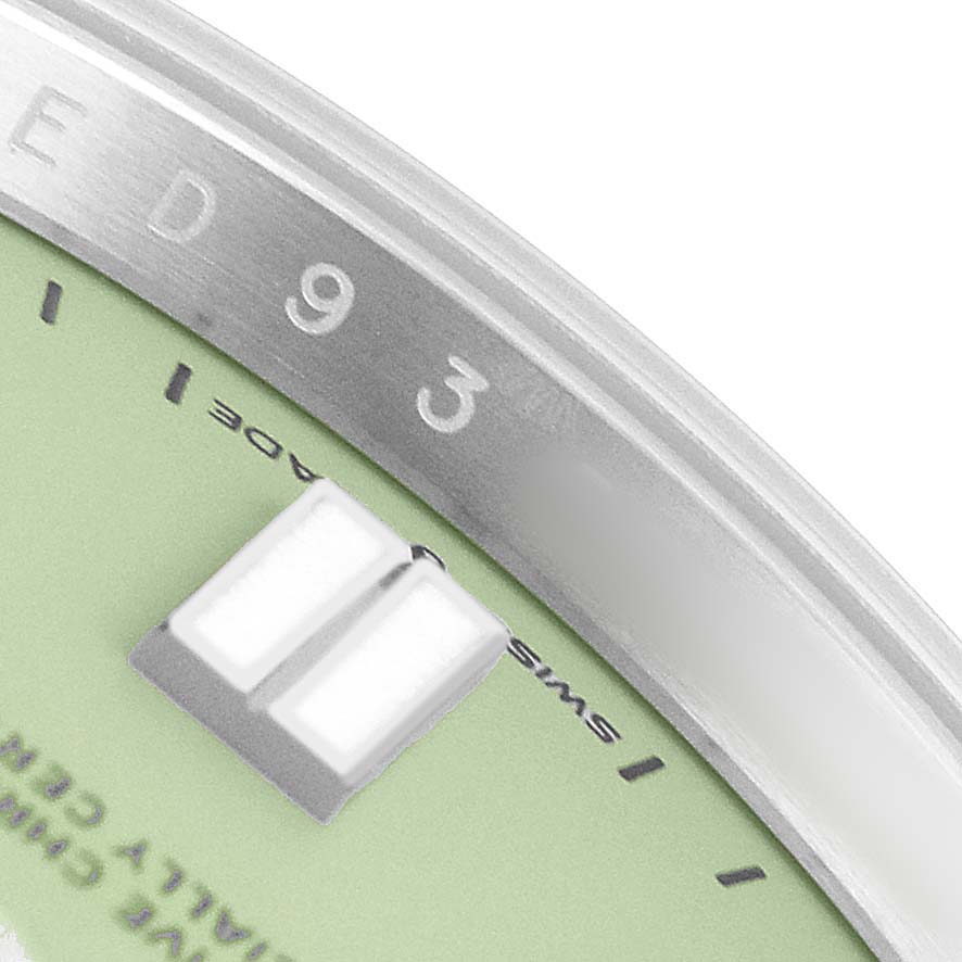 The image shows a close-up of the dial and part of the bezel of a Rolex Oyster Perpetual 134300 Men's Stainless Steel Green Dial watch.