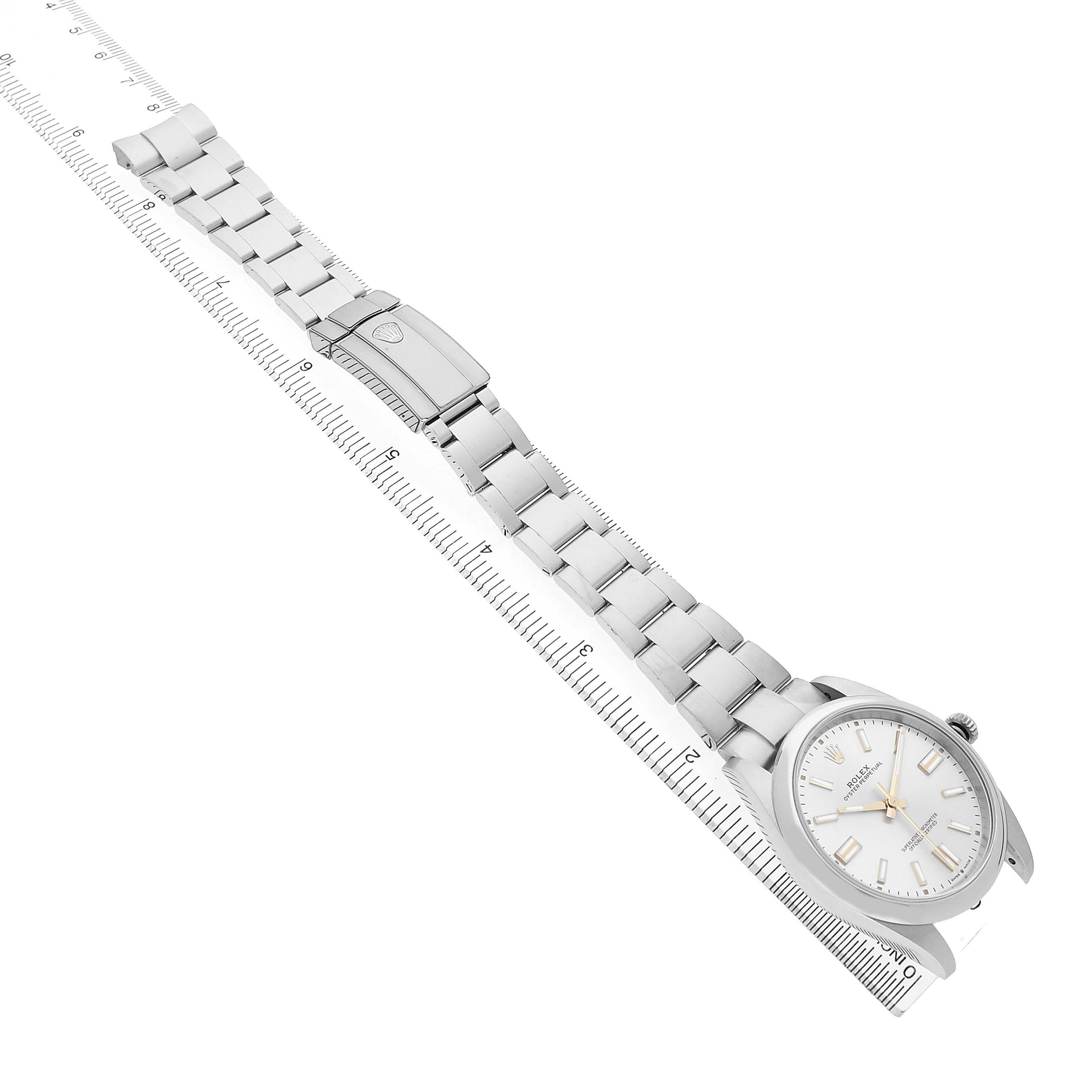 The Rolex Oyster Perpetual 124300 Men's Stainless Steel Silver Dial watch is shown from a top-down angle, displaying the bracelet, clasp, and face alongside a ruler.