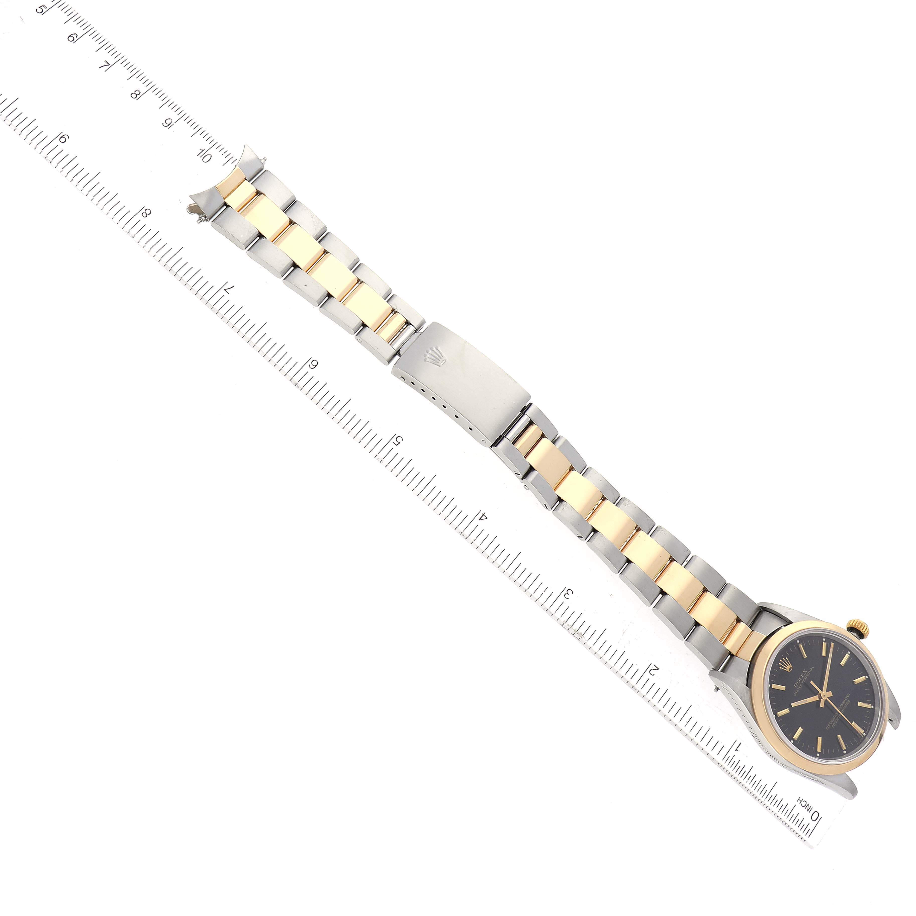 This image shows a top view of a Rolex Oyster Perpetual 14203 Men's Steel and Gold (two tone) Black Dial 14203 Men's Steel and Gold (two tone) Black Dial watch, displaying its band and dial next to a ruler for scale.