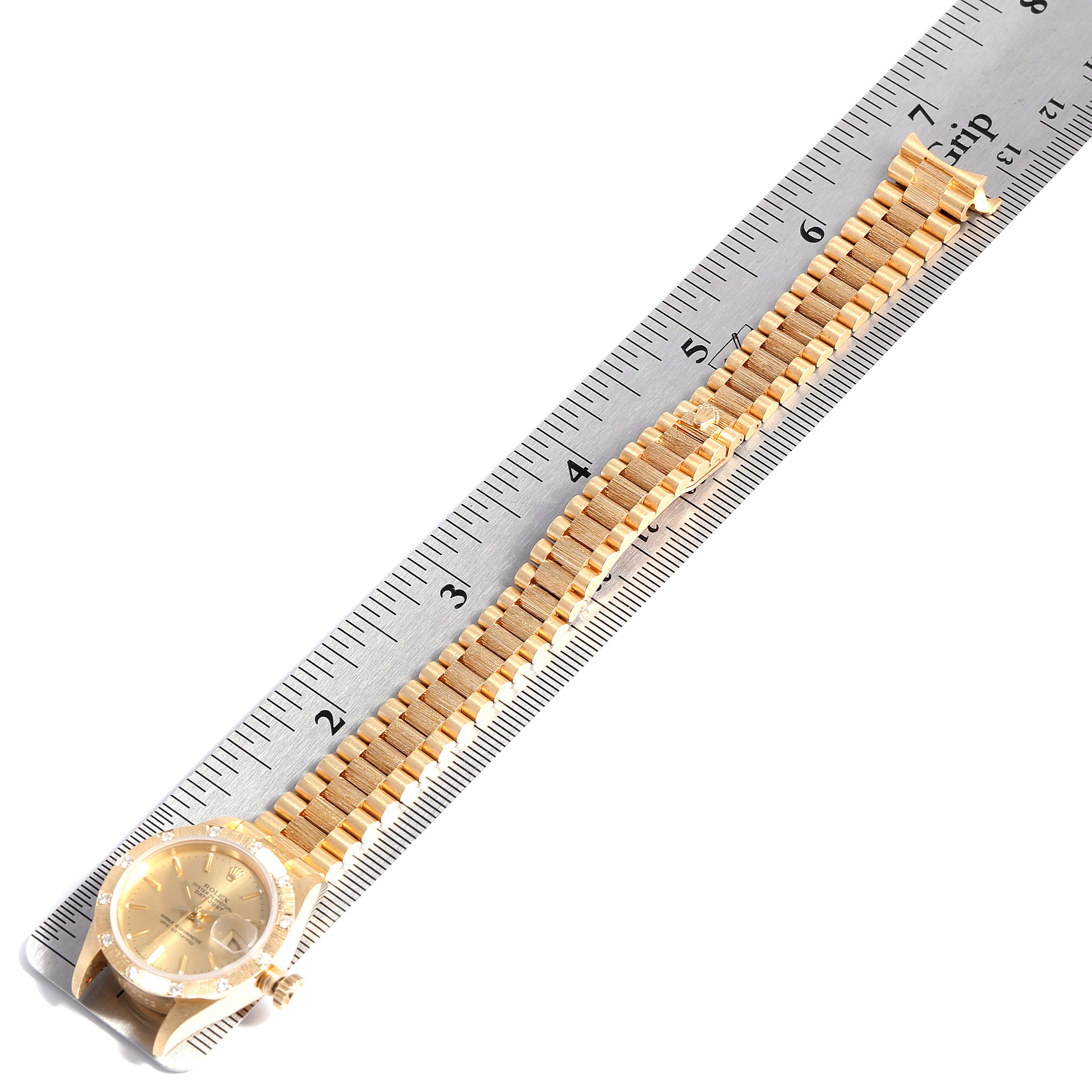 The image shows a Rolex President 69288 Women
s Yellow Gold Champagne Dial 69288 Women
s Yellow Gold Champagne Dial model watch laid flat with its bracelet extended beside a ruler.