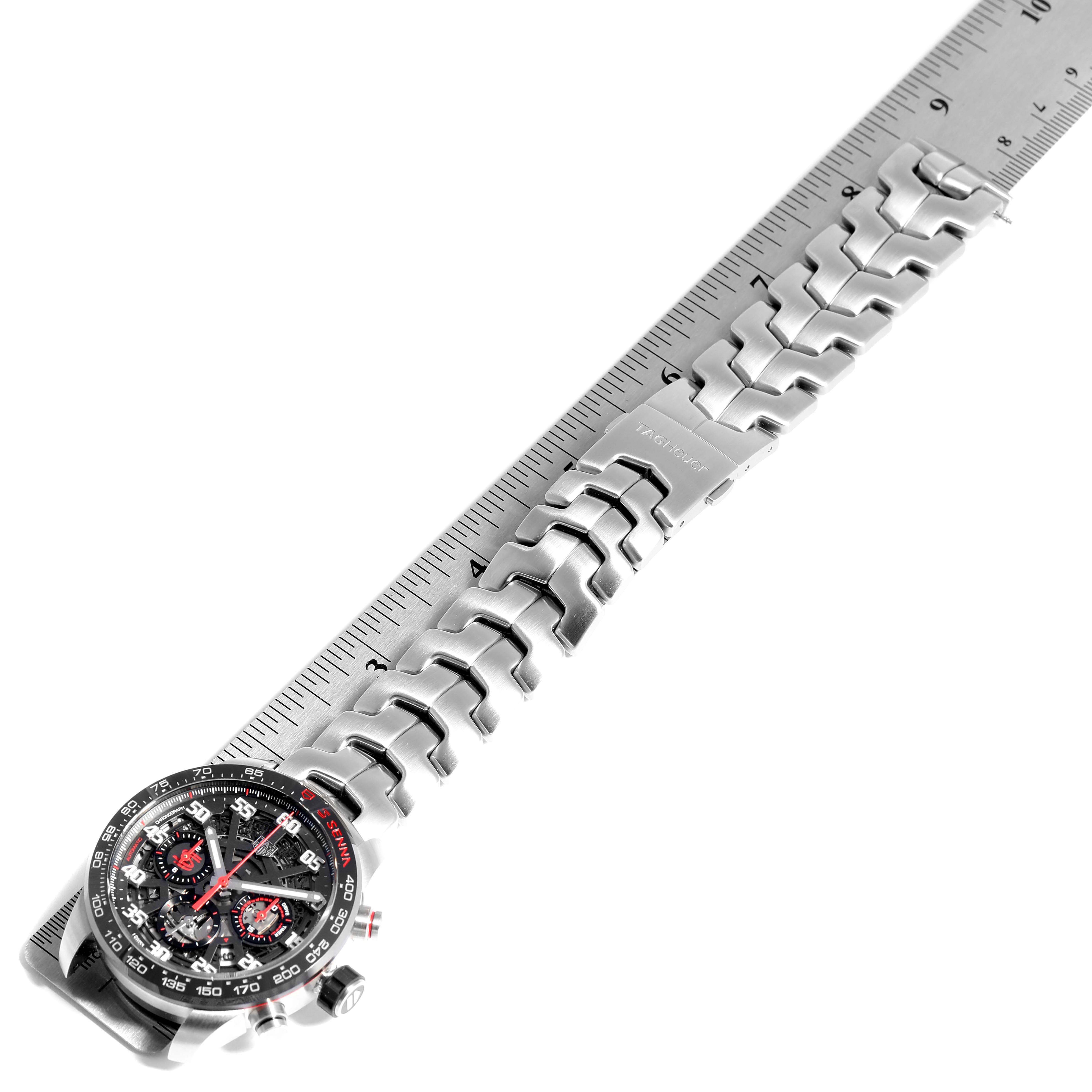 The image shows a Tag Heuer Carrera CBG2013.BA0657 Men's Stainless Steel Transparent Dial CBG2013.BA0657 Men's Stainless Steel Transparent Dial watch laid flat on a ruler, displaying the watch face and metal band.