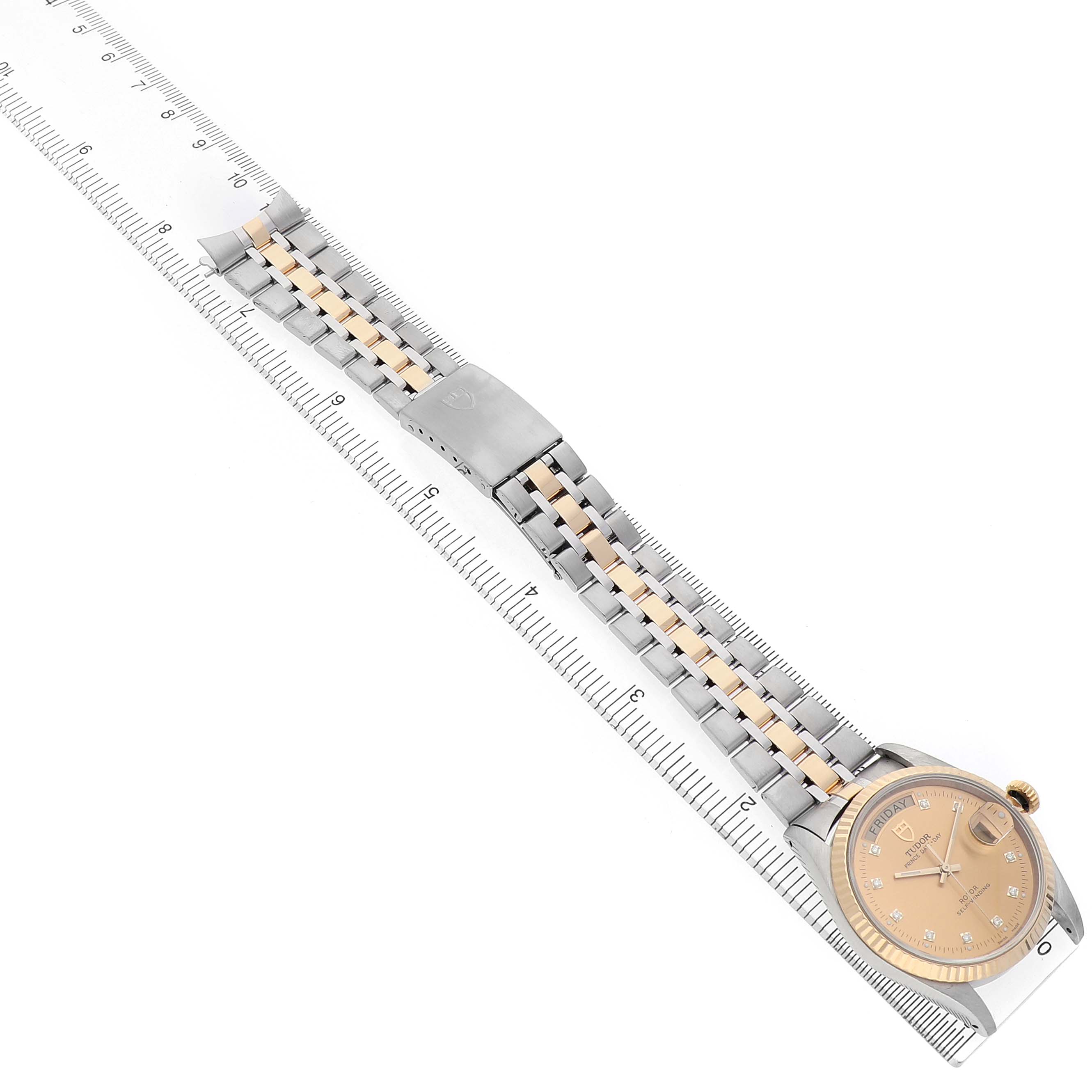The Tudor Prince 76213 Men's Stainless Steel Champagne Dial watch is shown from the top, displaying its face, bracelet, and clasp along a measuring ruler.
