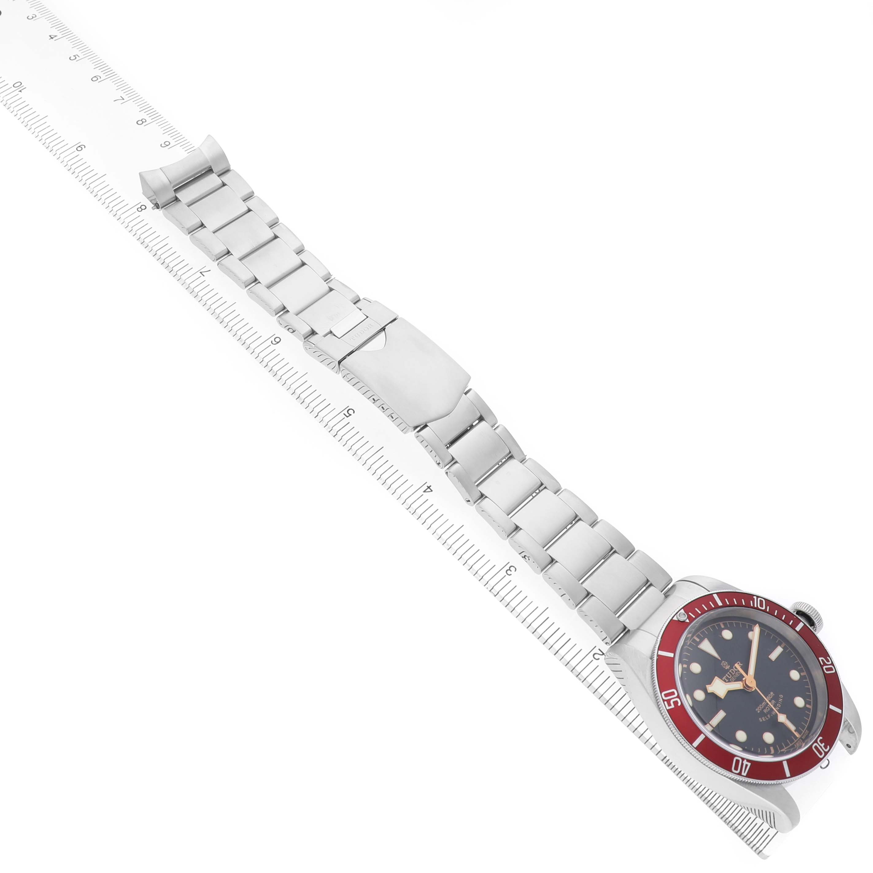 The Tudor Heritage Black Bay 79220R Men's Stainless Steel Black Dial watch is shown from a top view, highlighting the full stainless steel bracelet and face with a bezel.