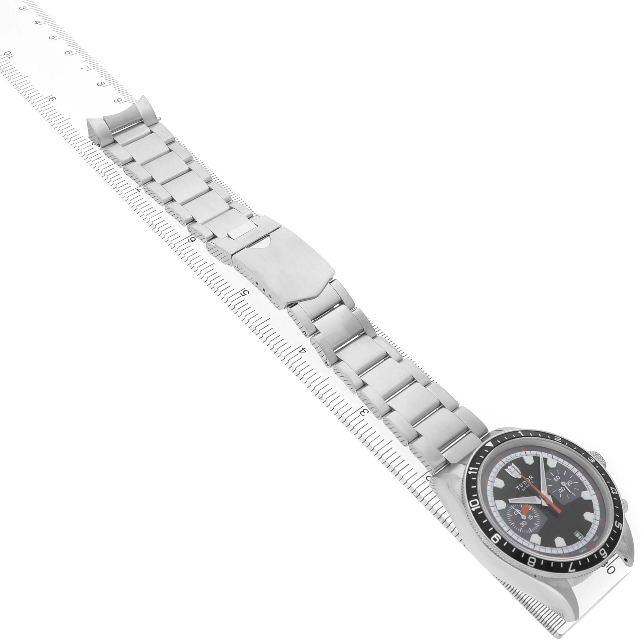 The image shows a Tudor Heritage Chrono 70330N Men's Stainless Steel Black Dial watch diagonally, highlighting the face, bezel, and linked bracelet.