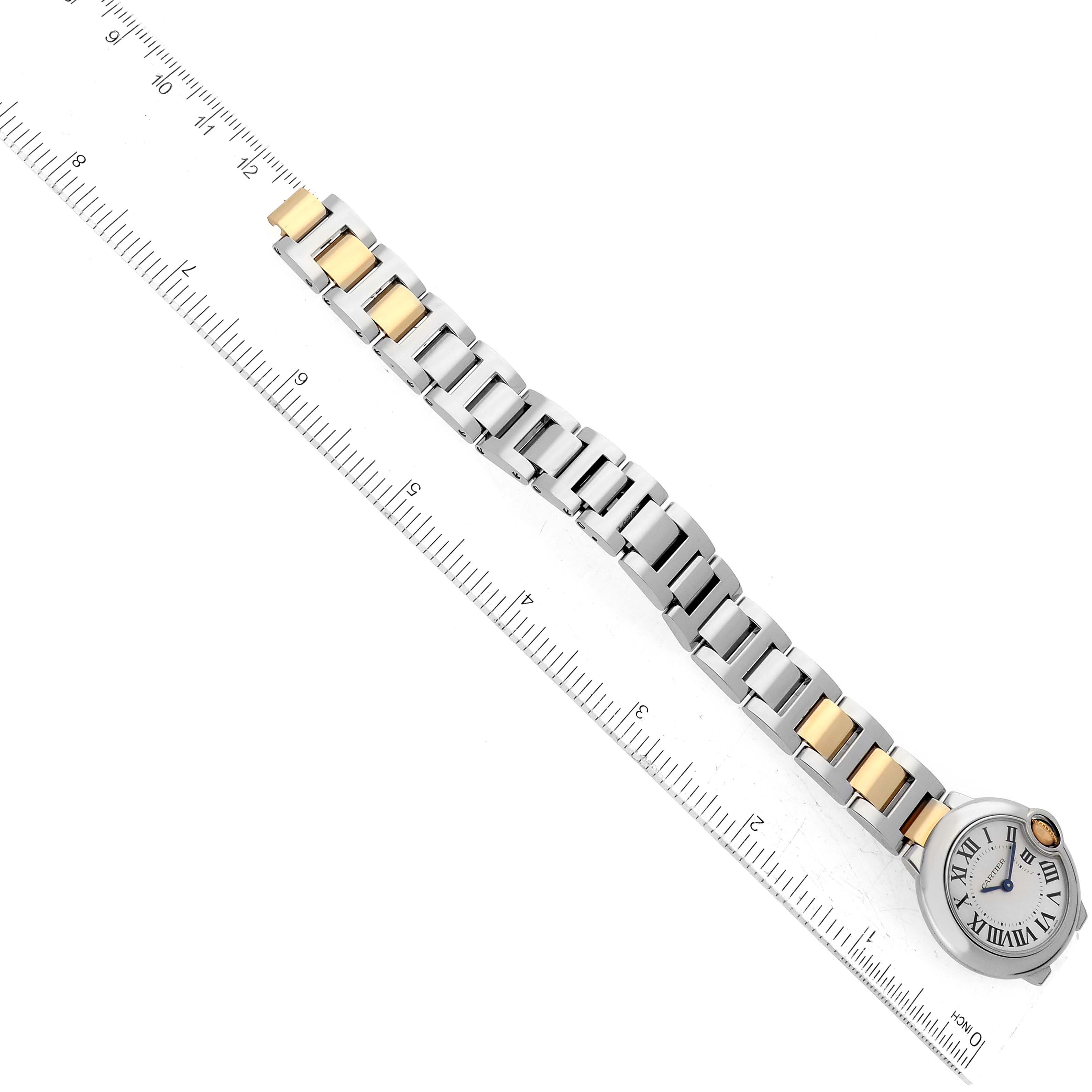 The image shows the Ballon Bleu model watch by Cartier diagonally, highlighting its face and bracelet next to a ruler.