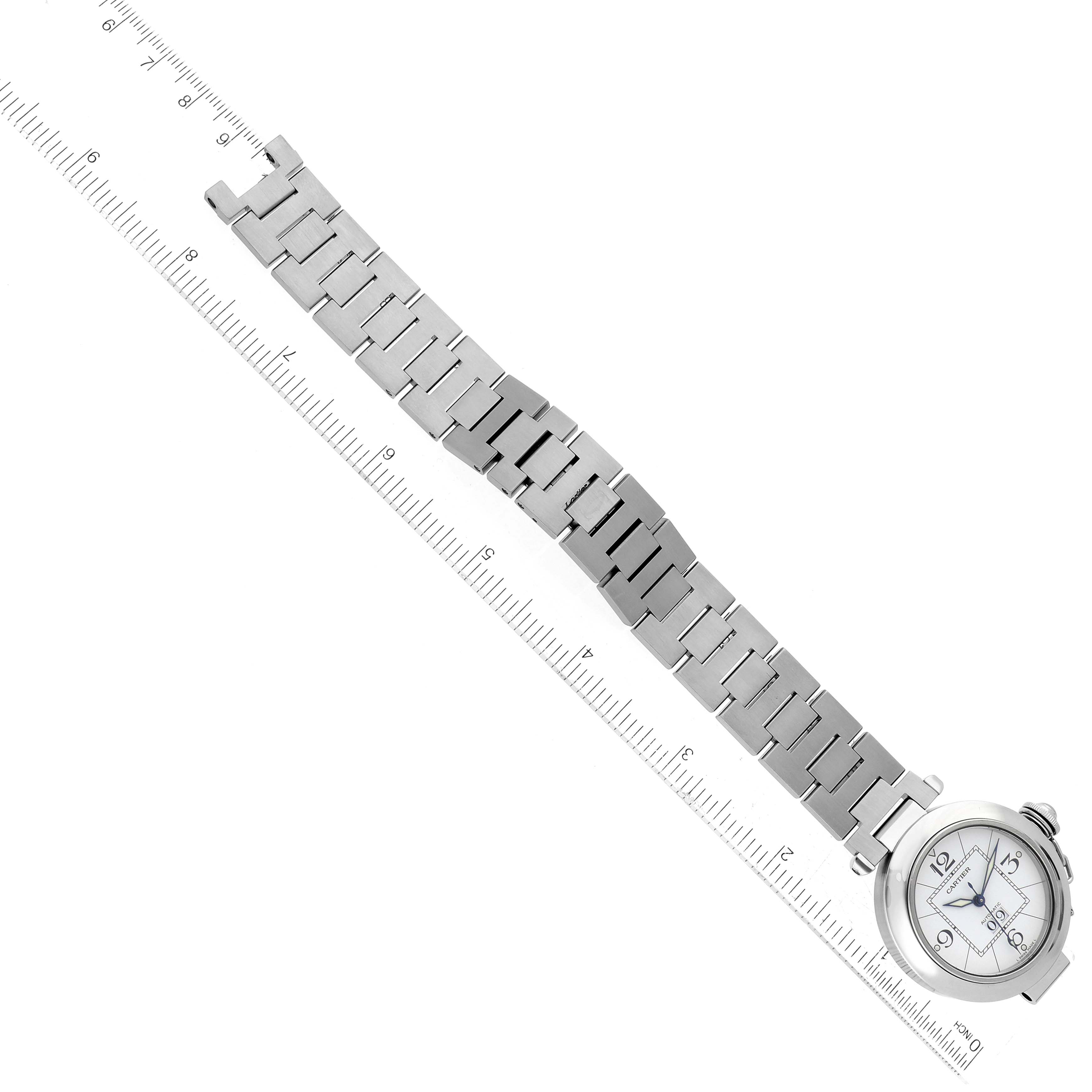This image shows a Cartier Pasha 63488 Men's Stainless Steel White Dial 63488 Men's Stainless Steel White Dial watch laid flat, with its metal band and face visible, alongside a ruler for scale.
