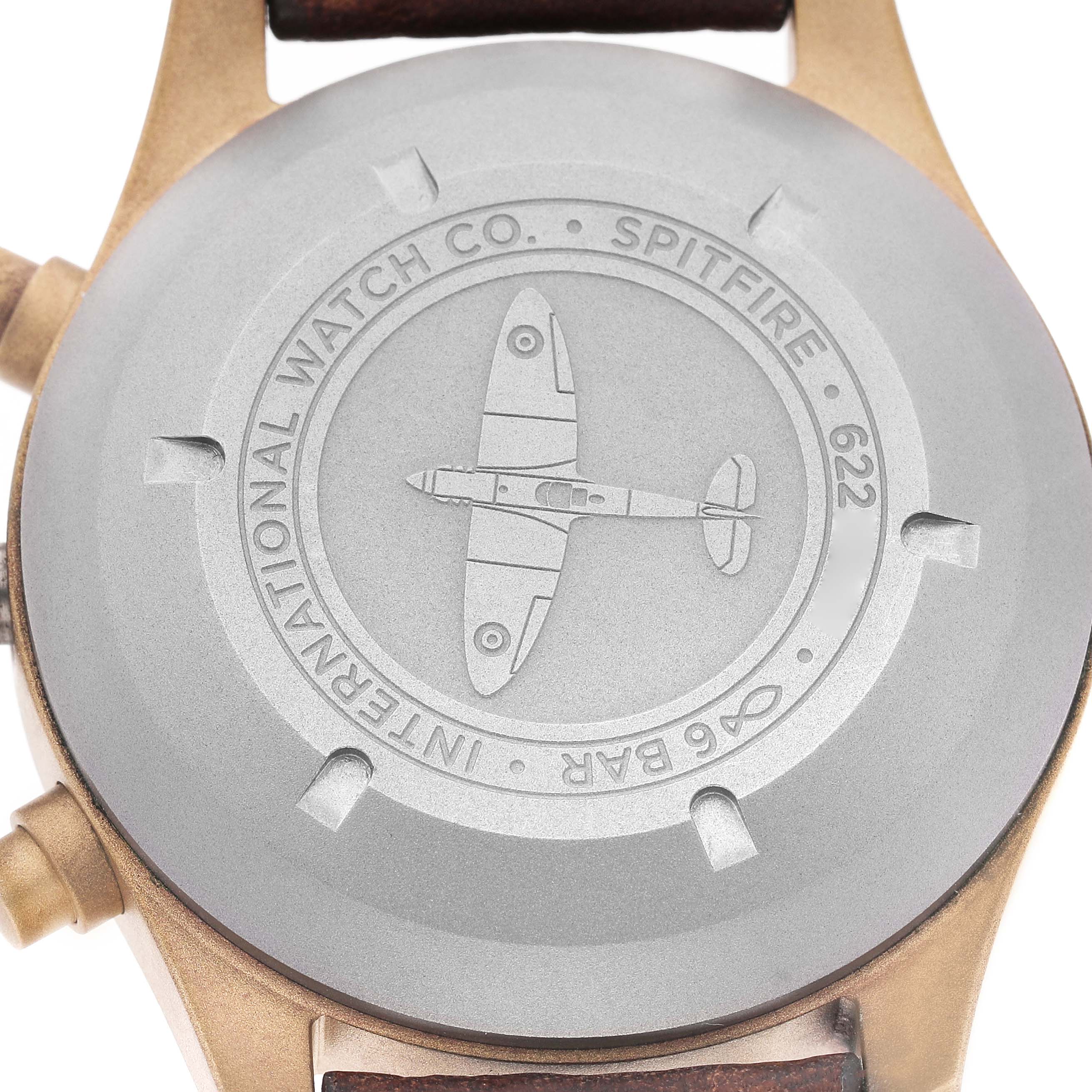 The image shows the case back of the IWC Pilot IW387902 Men's Bronze Green Dial model watch, featuring an engraved Spitfire design.