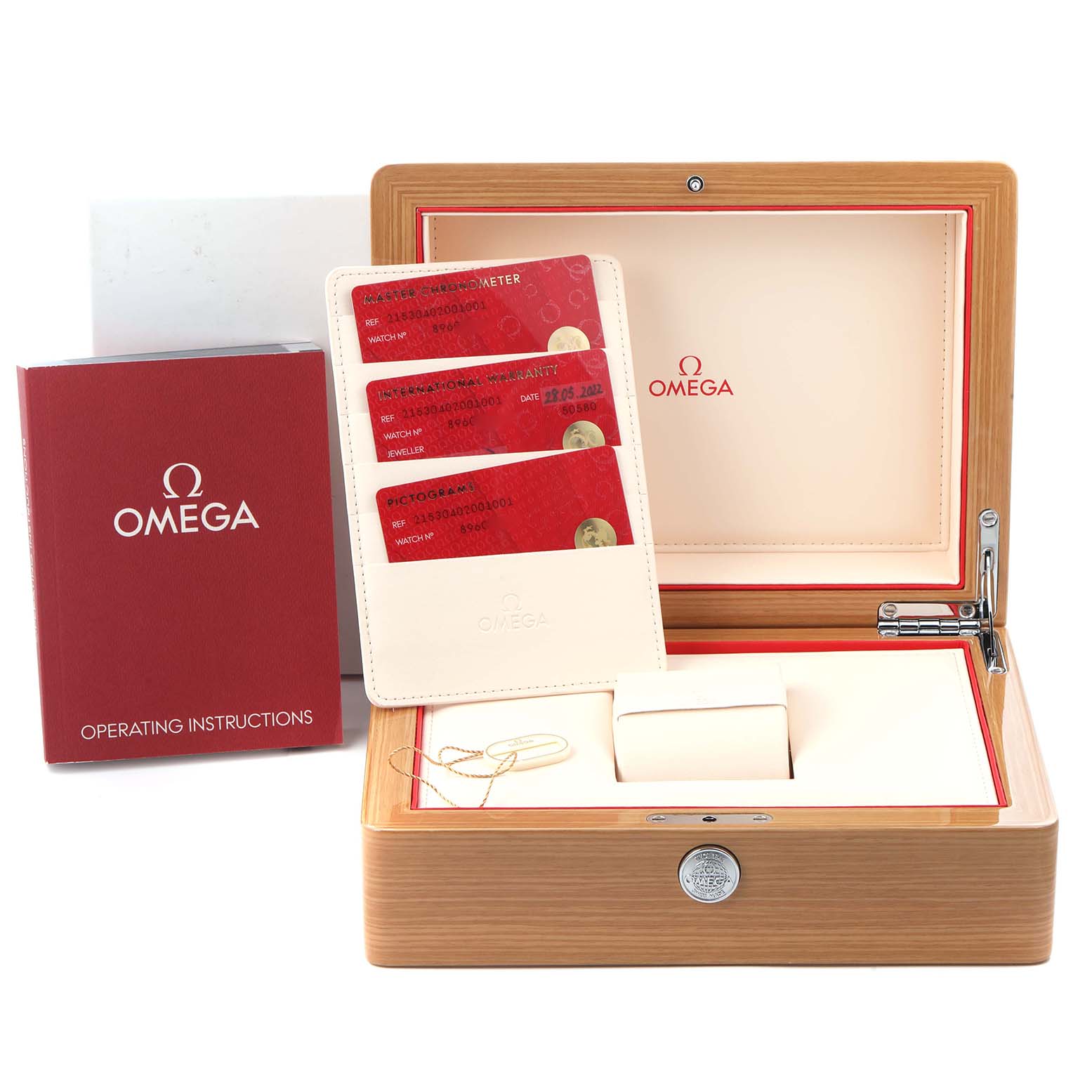 The image shows the packaging and accessories for the Omega Planet Ocean model 215.30.40.20.01.001, including a wooden box, cards, and instruction booklet.