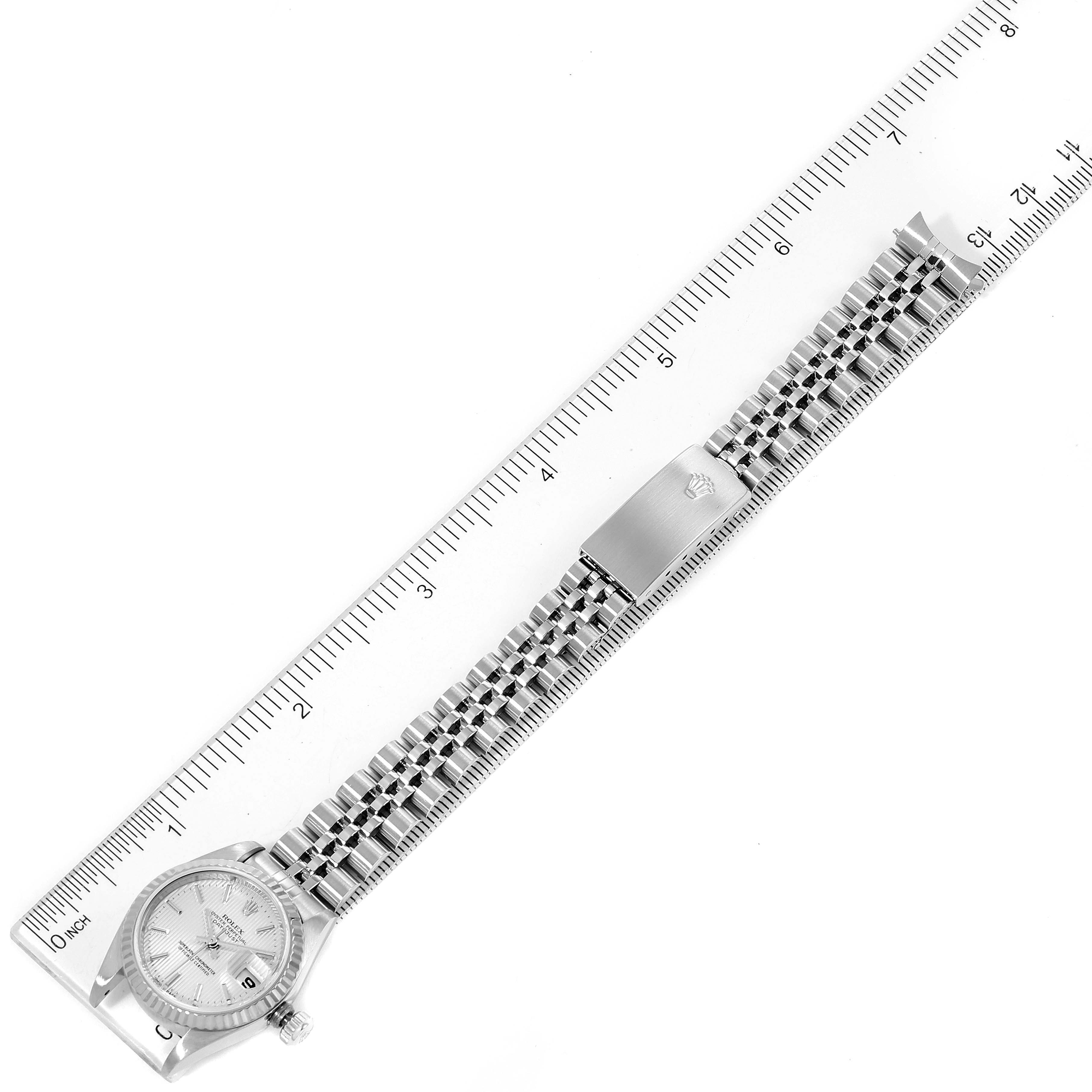 The image shows a top-down view of a Rolex Datejust 79174 Women
s Stainless Steel Silver Dial 79174 Women
s Stainless Steel Silver Dial watch, including the bezel, dial, bracelet, and clasp, measured next to a ruler.