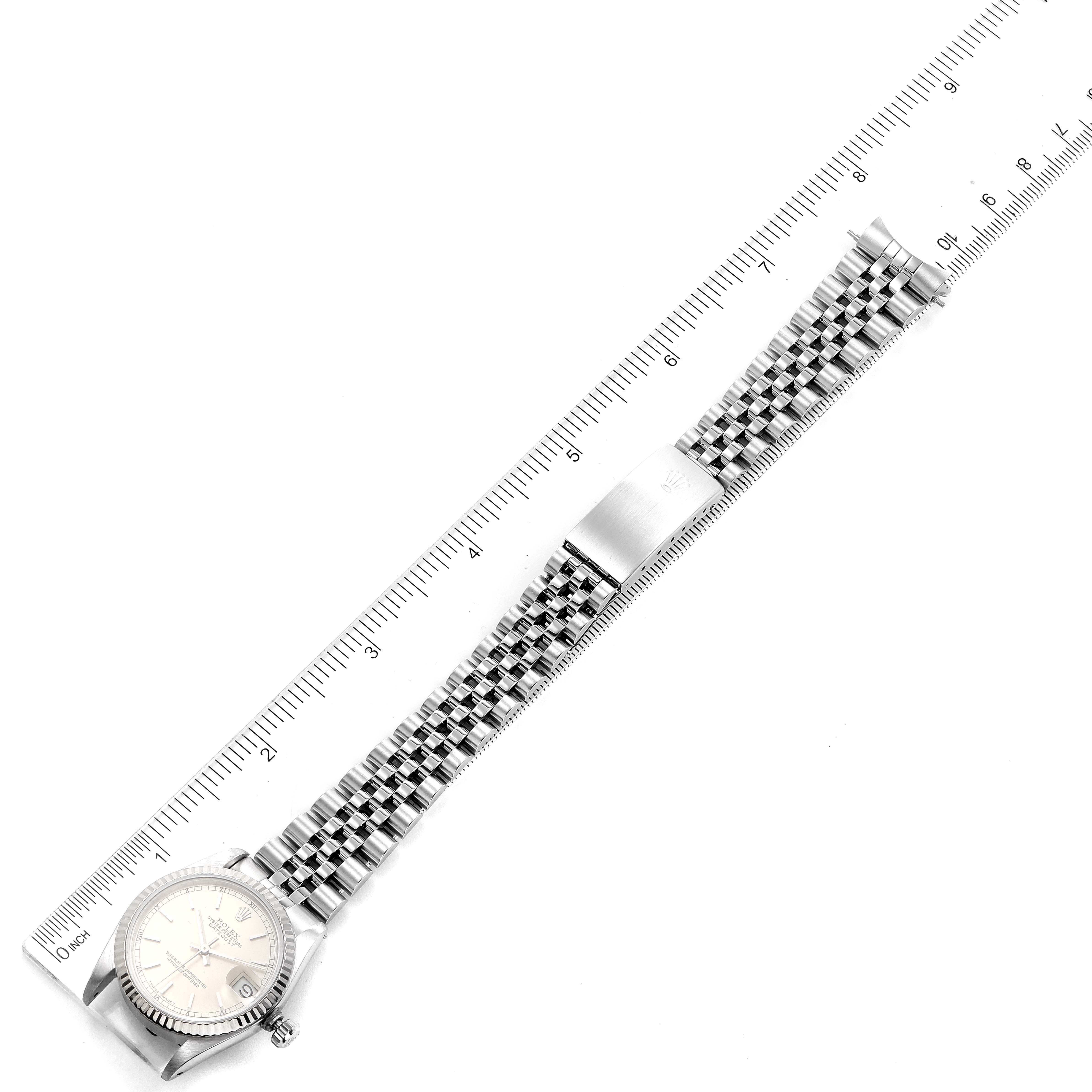 This image shows a top-down view of a Mid-Size Rolex watch with its metal bracelet laid straight and a ruler for measurement.