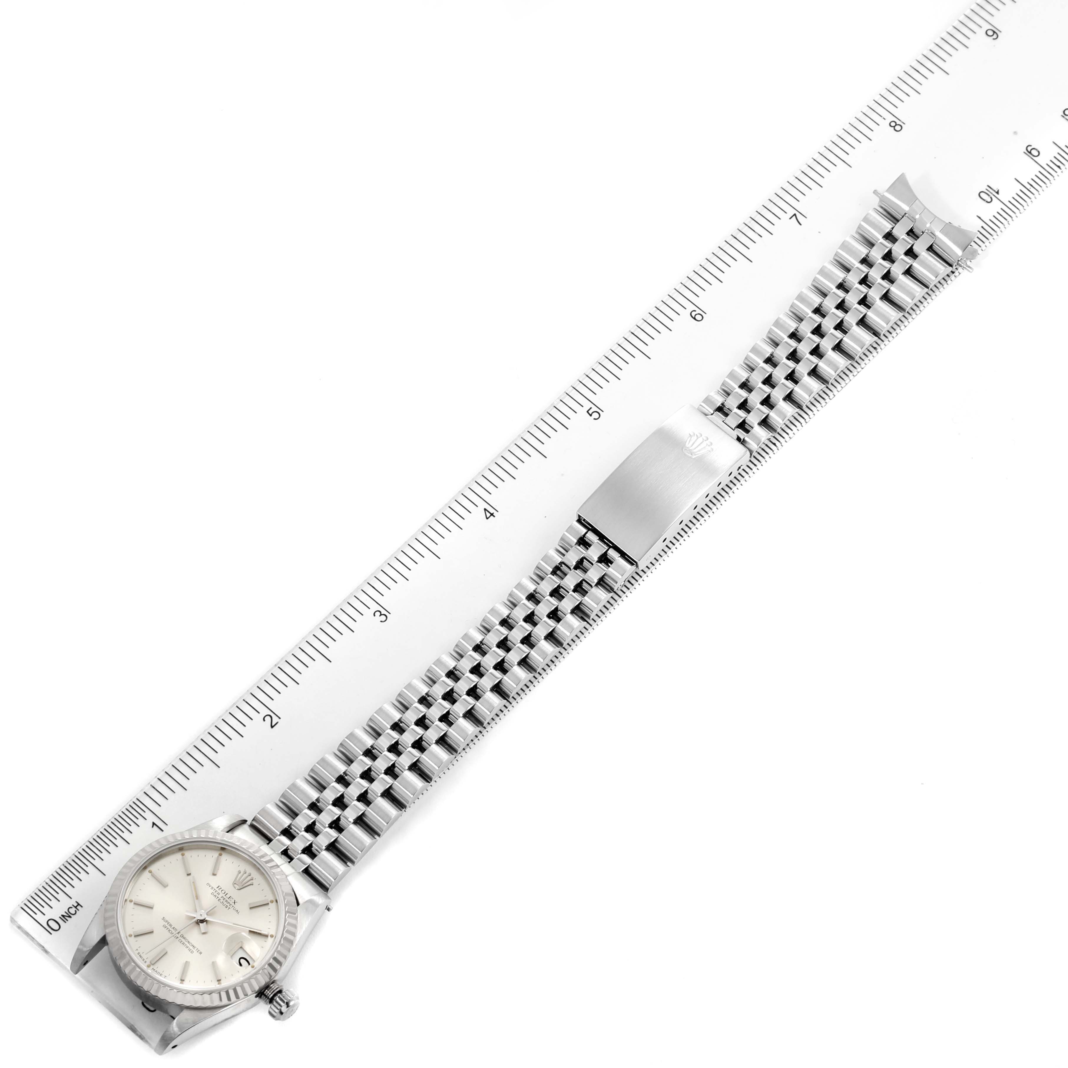 The image shows a top-down view of a Rolex Mid-Size 68274 Women
s Stainless Steel Silver Dial 68274 Women
s Stainless Steel Silver Dial watch with the bracelet and clasp alongside a ruler.