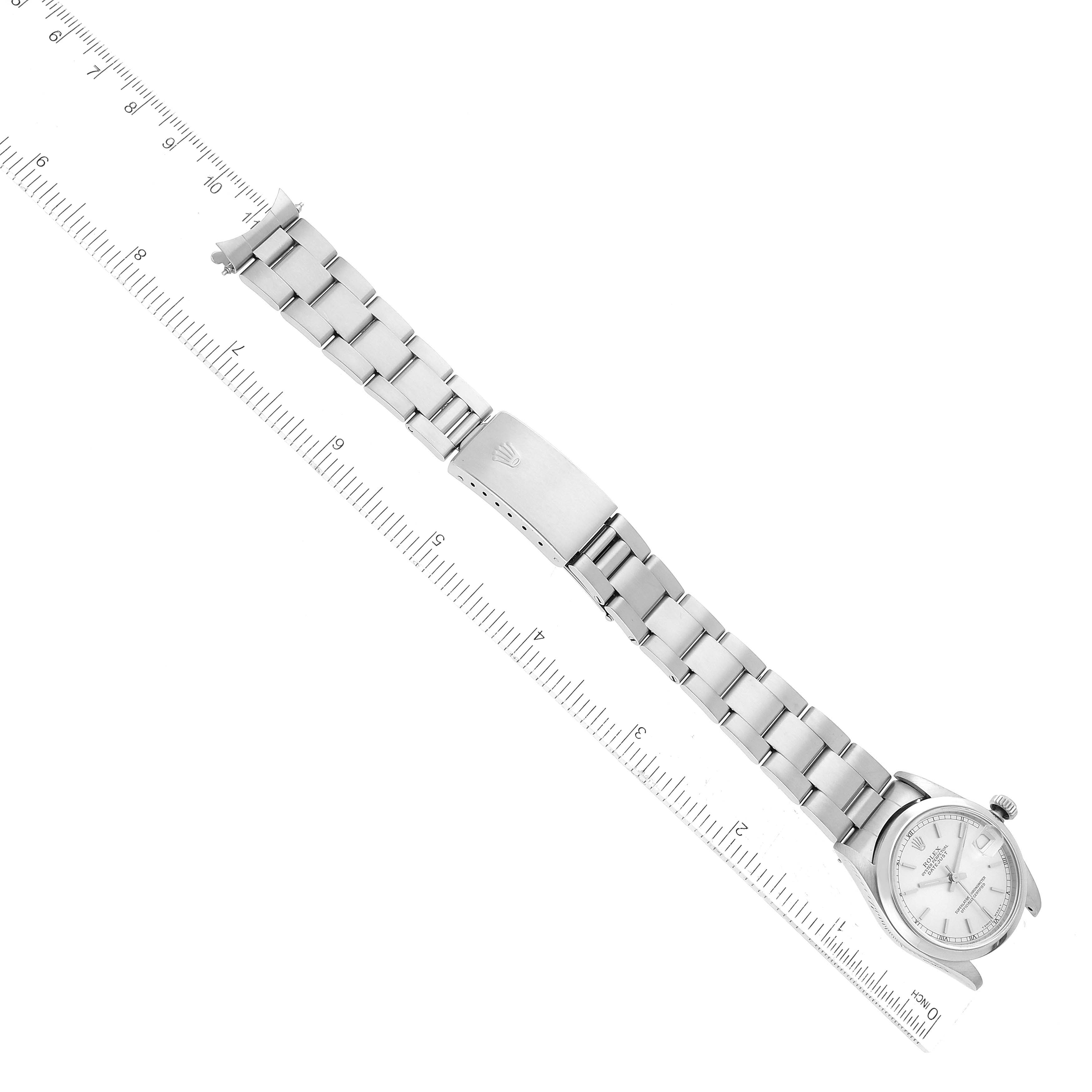 This image shows a flat, top-down view of a Rolex Mid-Size 68240 Women's Stainless Steel Silver Dial 68240 Women's Stainless Steel Silver Dial model watch, including its face, bracelet, and clasp lying along a ruler.